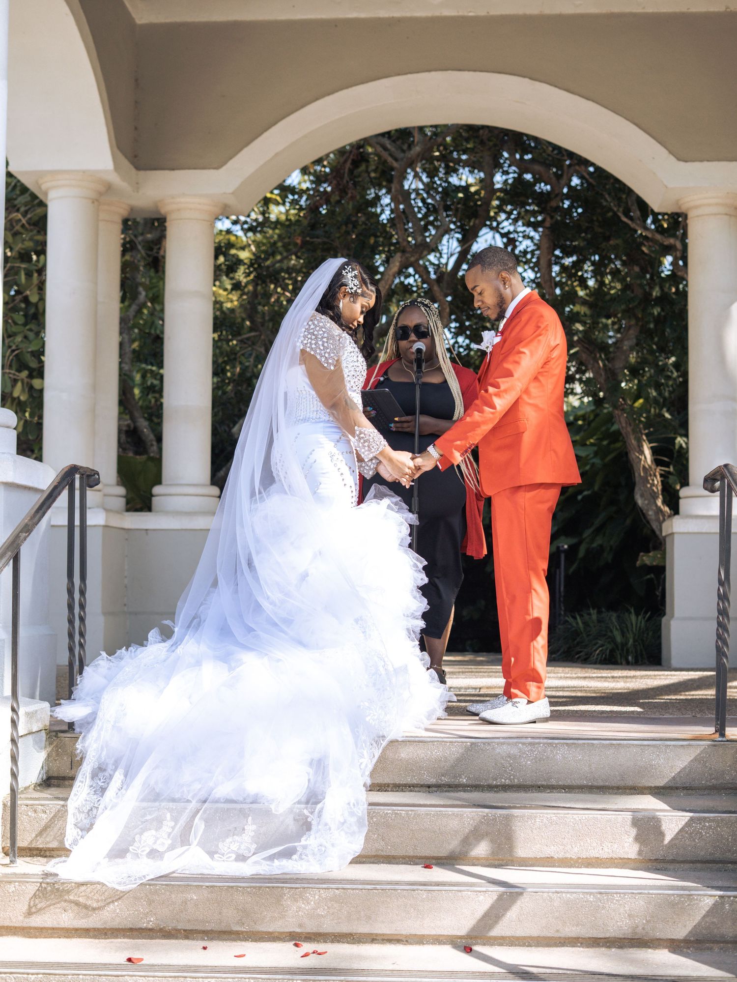 Wedding ceremony under white archway with couple exchanging vows.