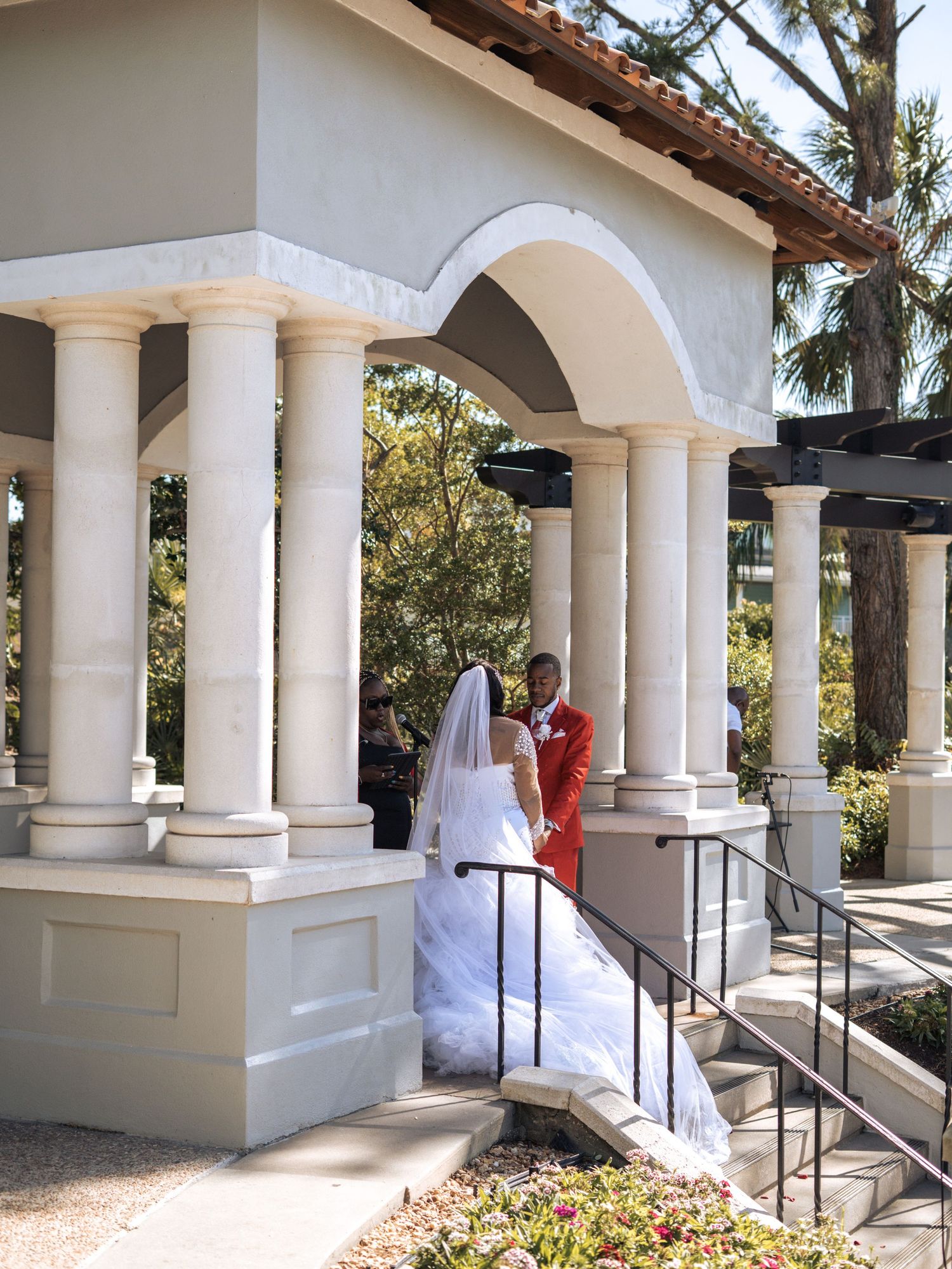 A couple at a Mediterranean-style venue with white columns and arches during their wedding ceremony.