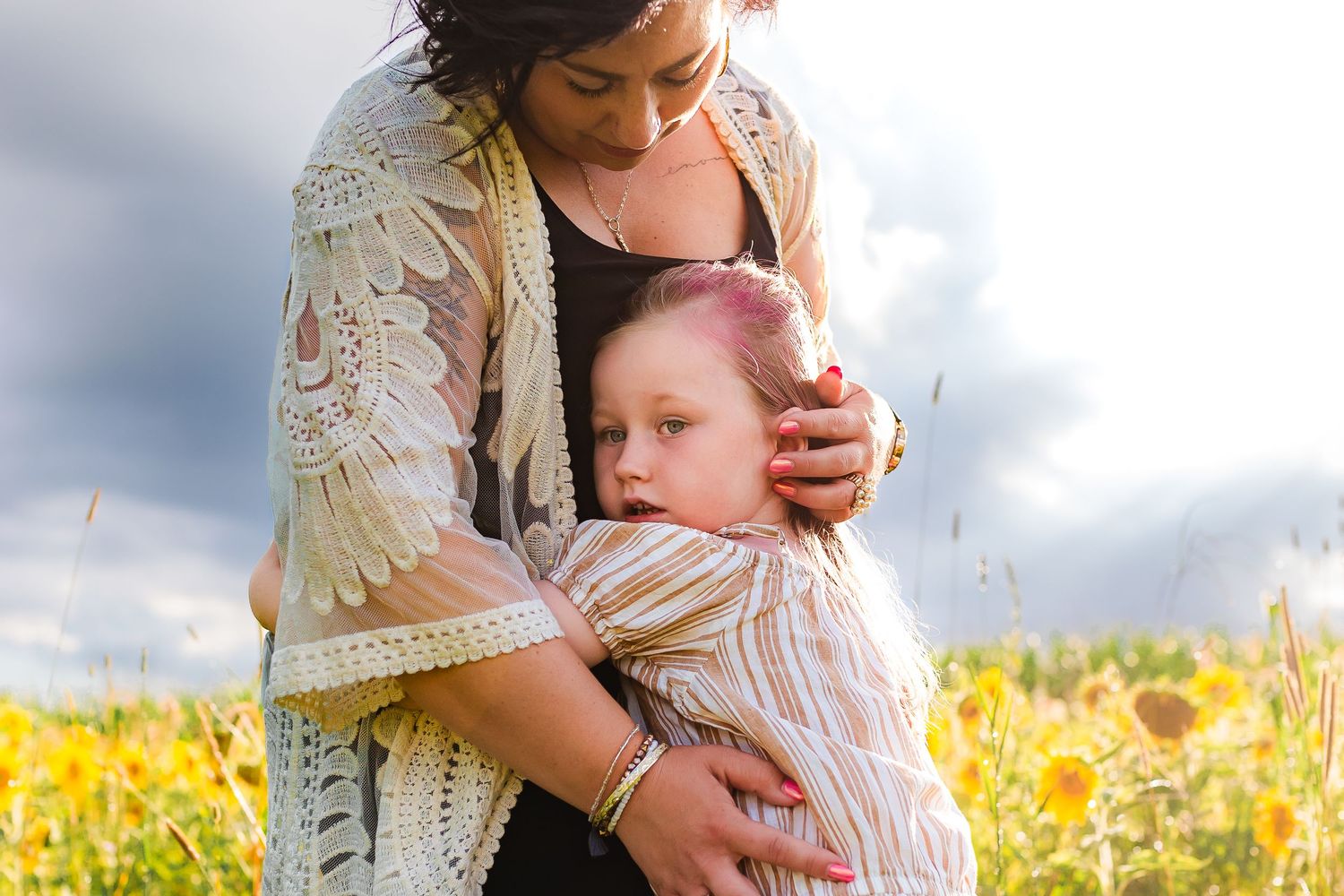A tender embrace in a sunny wildflower meadow, surrounded by yellow blooms and golden afternoon light.