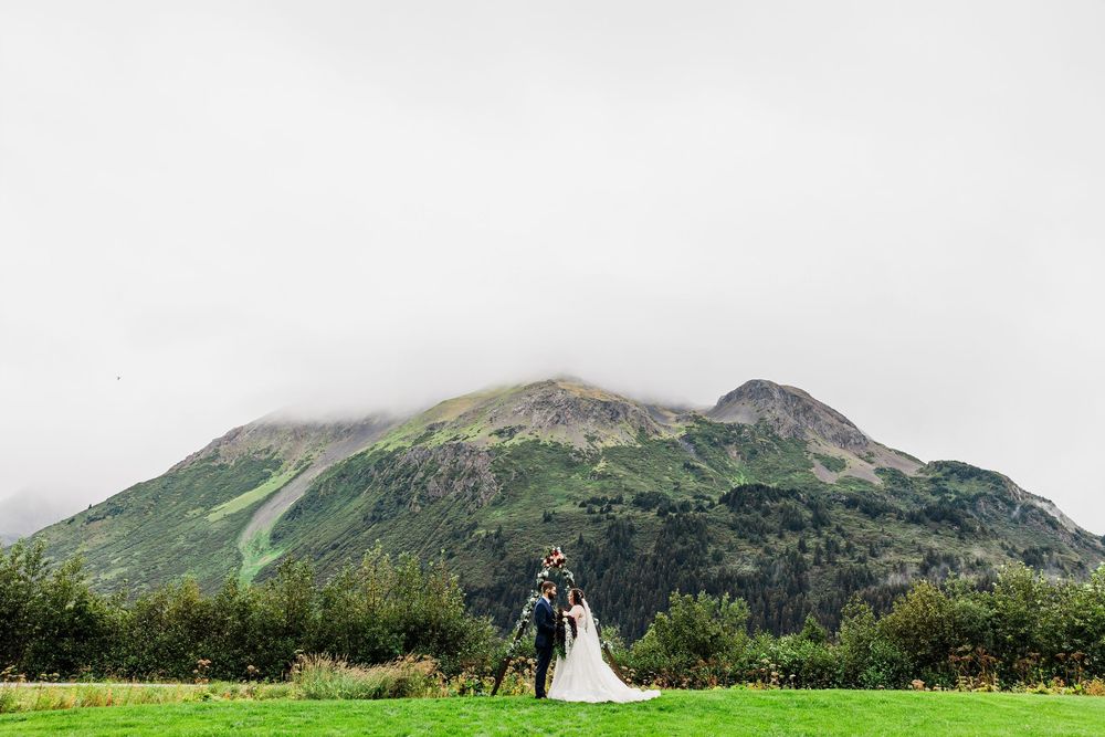 Minimalist wedding portrait with couple framed by vast mountain landscape.