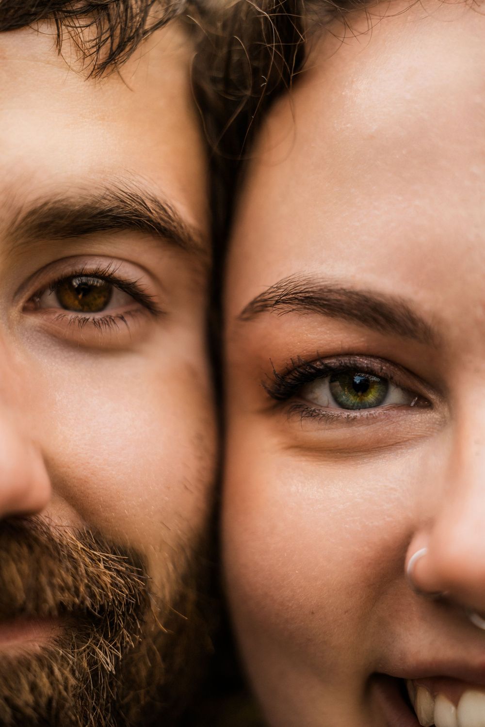 Extreme closeup of brown and green eyes with contrasting skin tones in an intimate portrait.