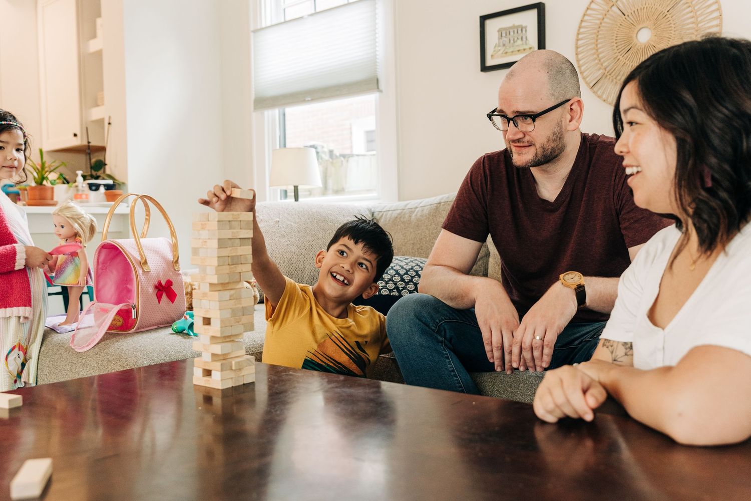 Family playing Jenga together at wooden table while enjoying quality time at home.
