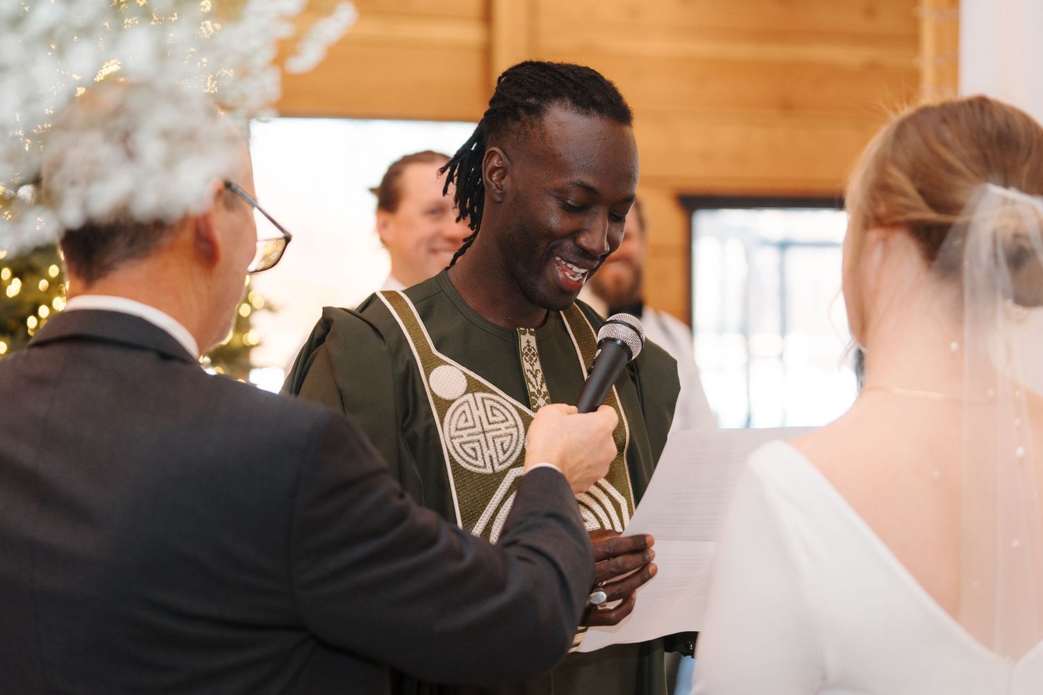 People share a joyful moment during a wedding ceremony in a warmly lit indoor venue.
