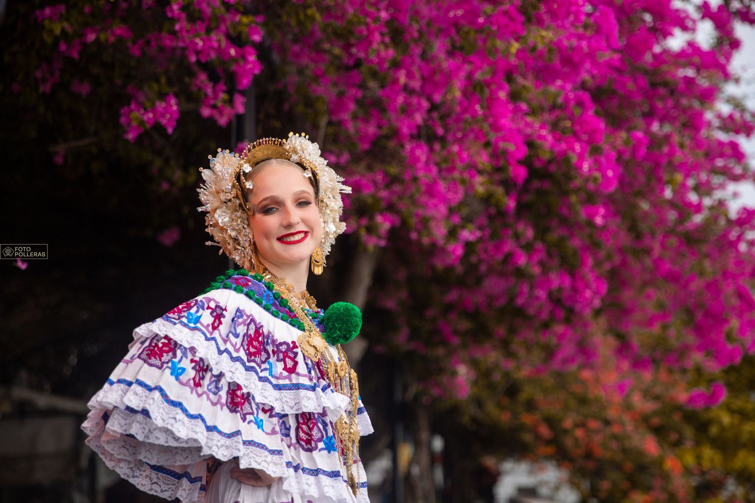 Mujer con pollera santeña de gala en sesión fotográfica en el casco antiguo con un fondo de flores de veraneras