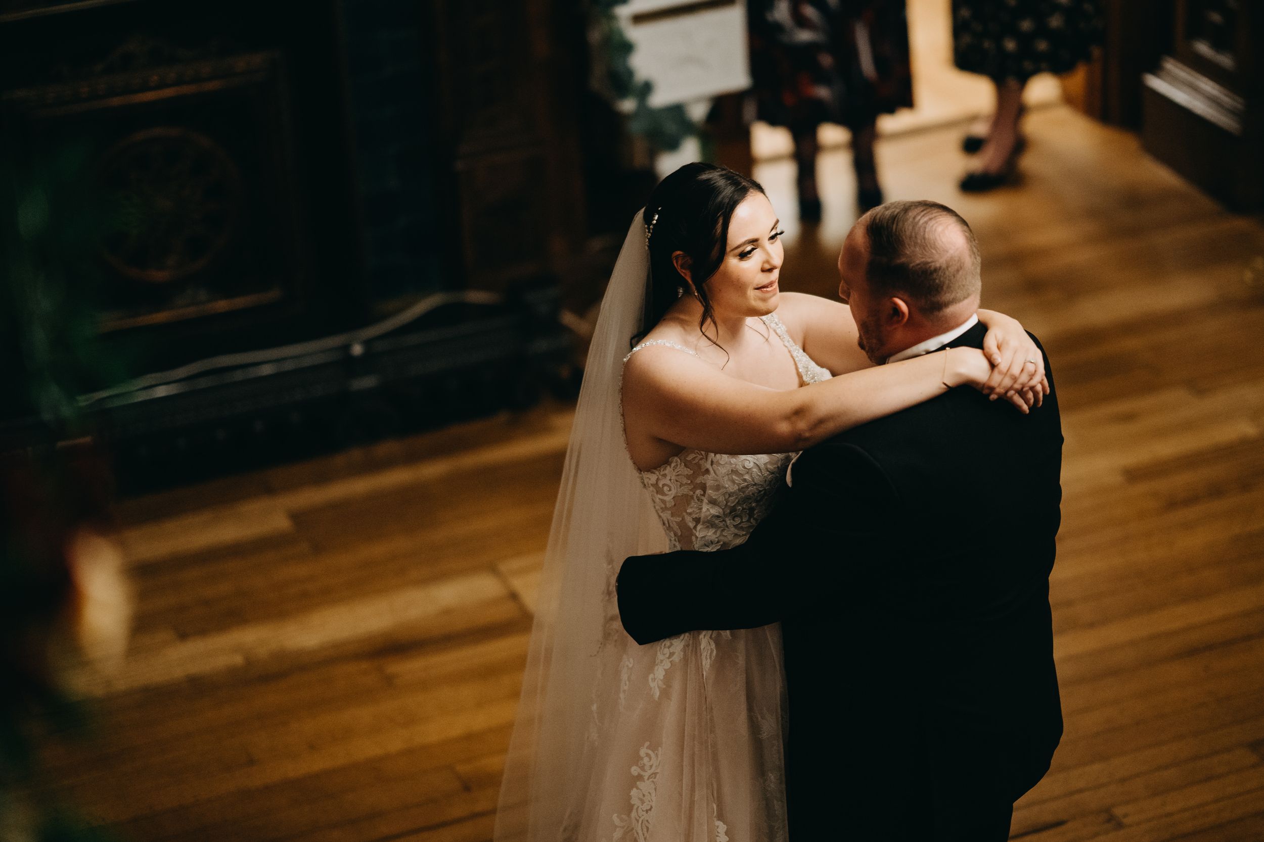 A couple shares an intimate dance together during their first dance at a wedding reception on a hardwood floor.