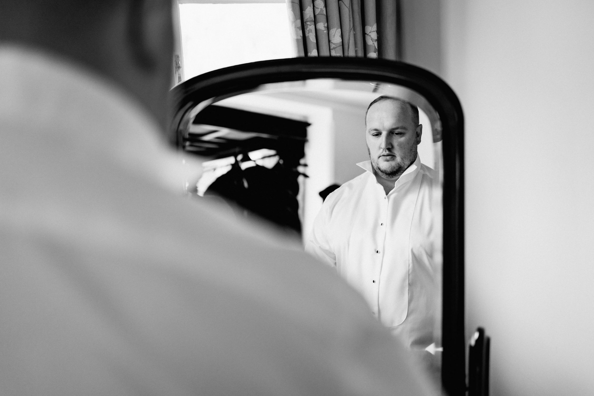 A black and white mirror reflection showing a dress shirt in soft lighting.