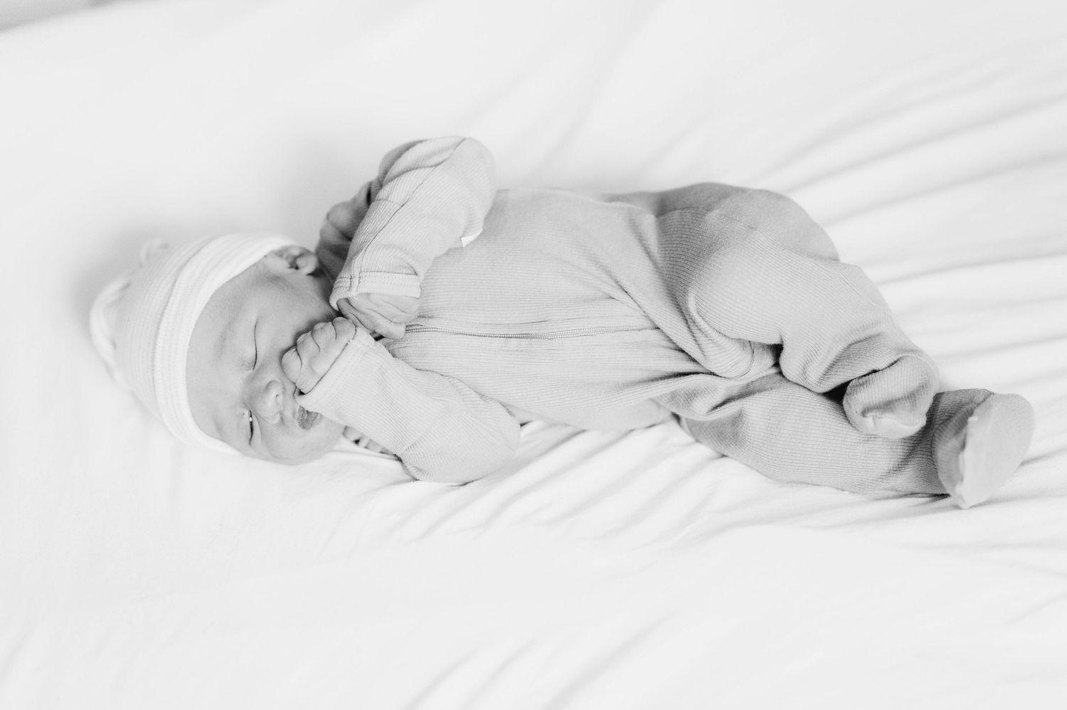 Newborn baby in light blue swaddle sleeps peacefully during a photo session.