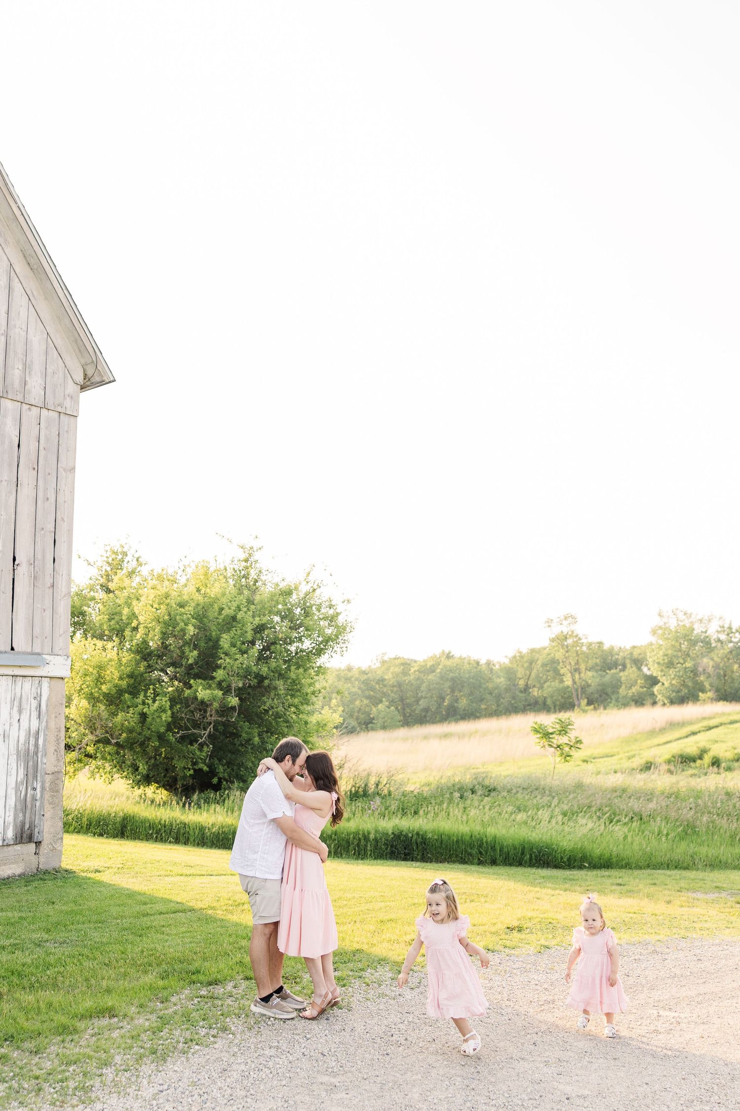A sweet outdoor portrait showing affection between parent and child in matching pink dresses on a sunny summer day.