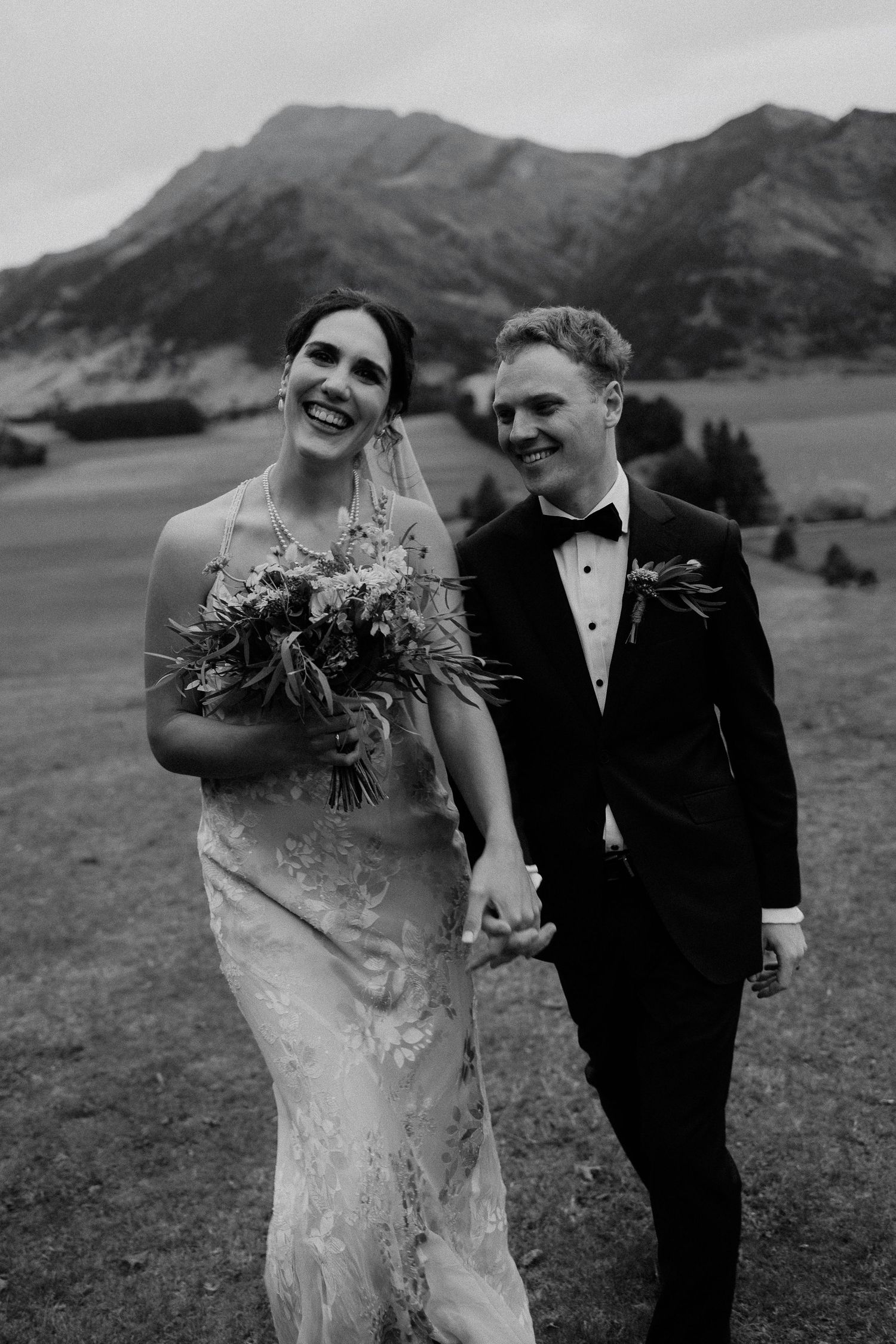 A bride and groom share romantic moments in a scenic mountain setting with black and white photography.
