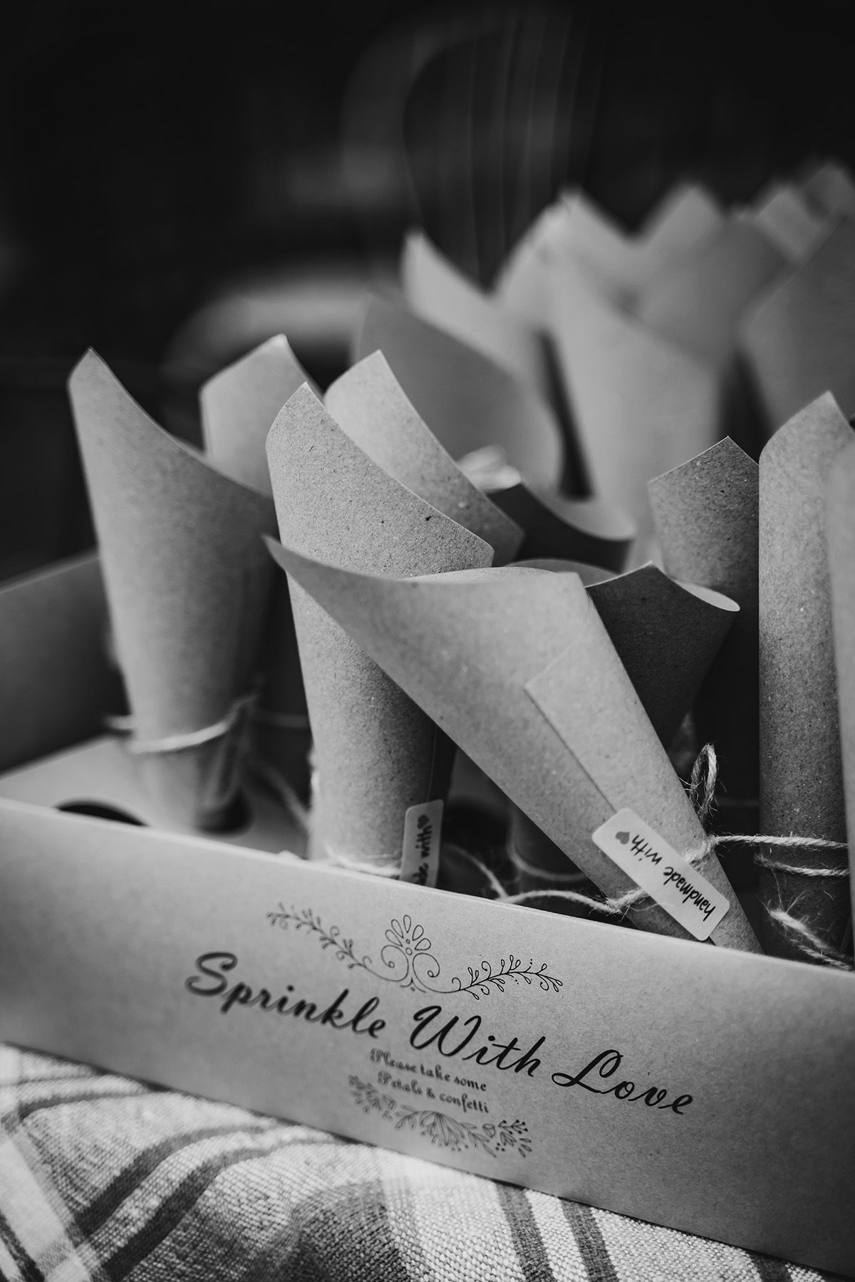 Svartvit bröllopsfoto med detalj av strutar med konfetti att kasta på brudparet. "Sprinkel with love" är tryckt på strutarna.