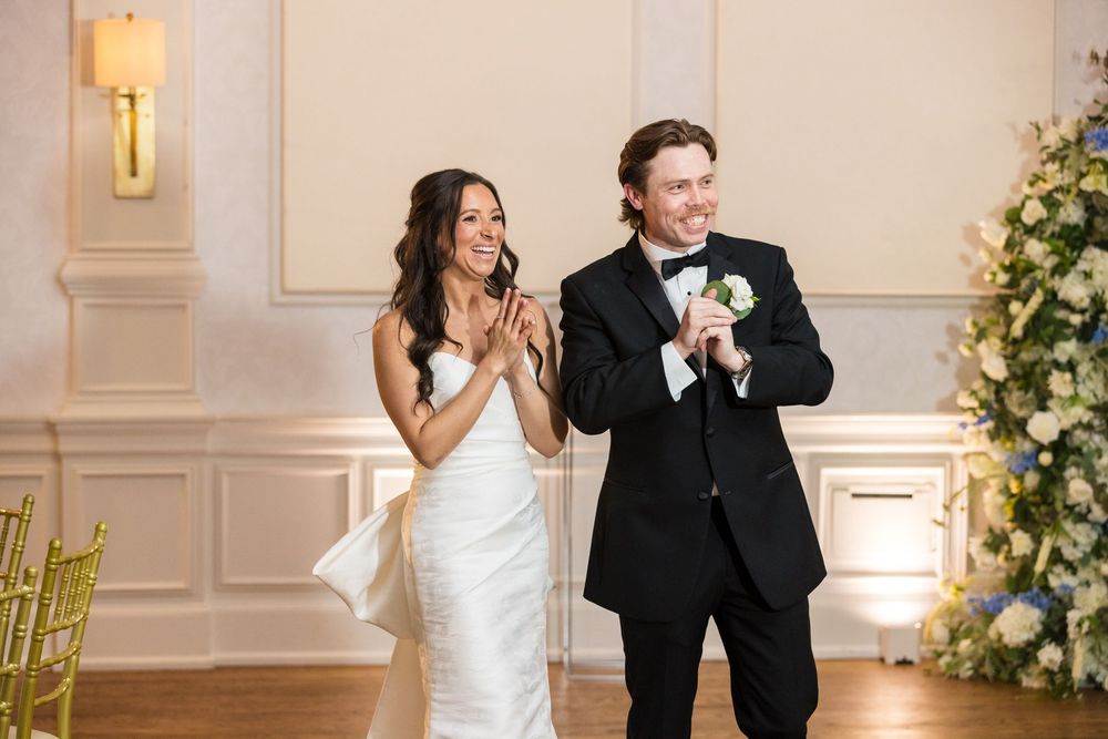 Happy couple celebrating during a joyful moment at an elegant wedding reception with floral decor.