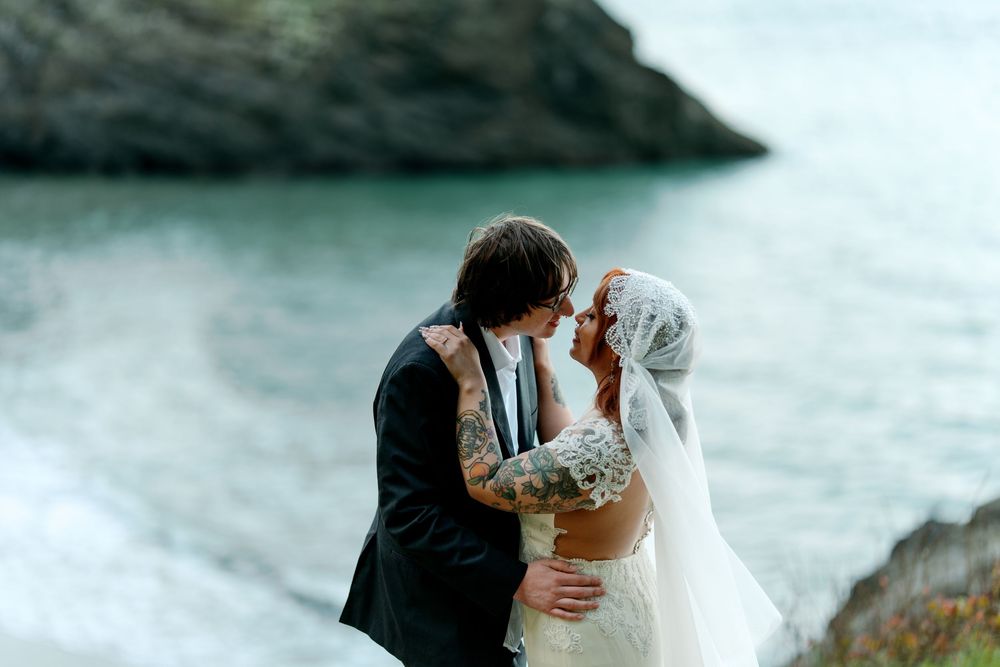 A romantic coastal wedding moment captured on a cliff overlooking turquoise waters.