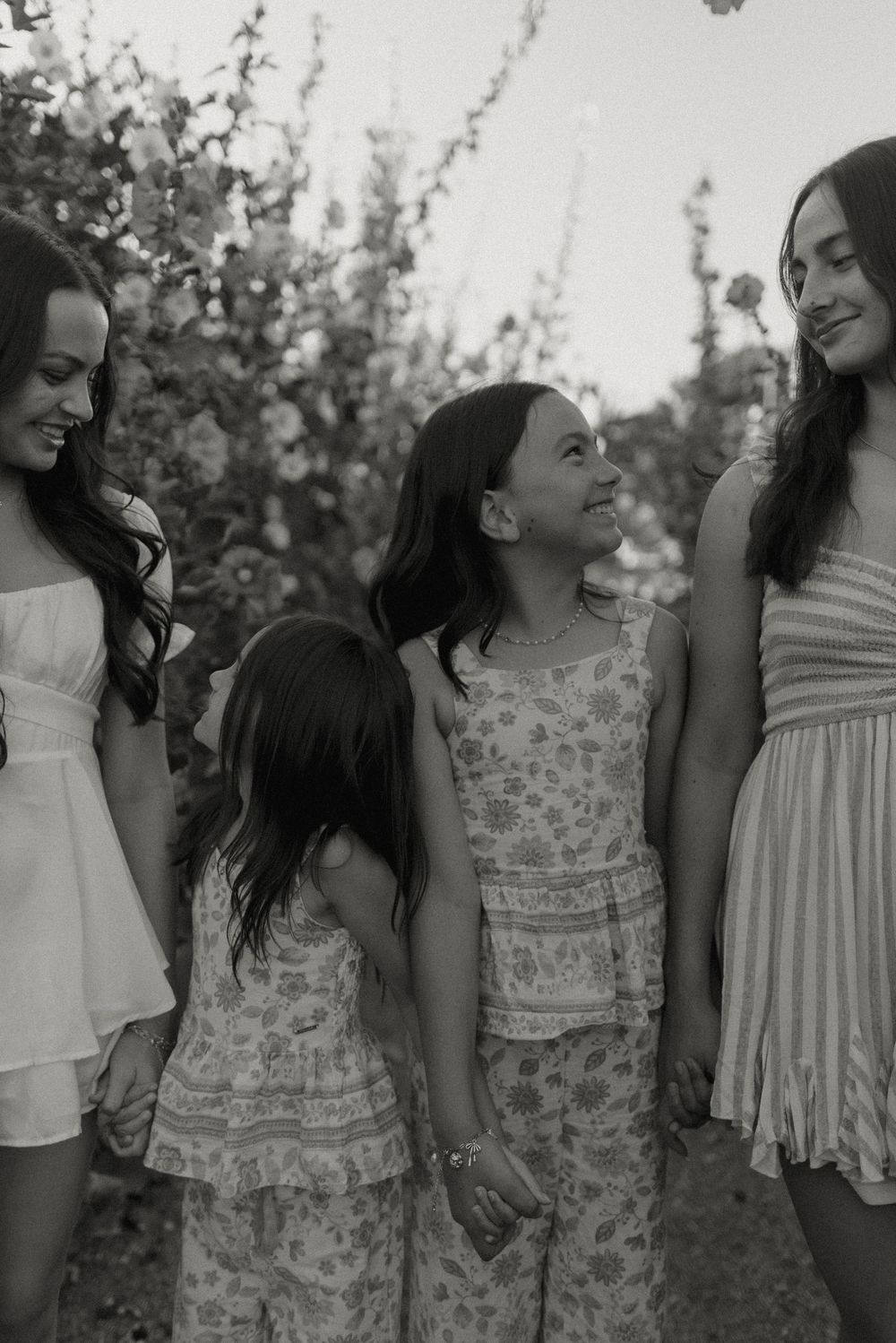 A group of young people interacting outdoors in casual spring attire, captured in a black and white photo series.