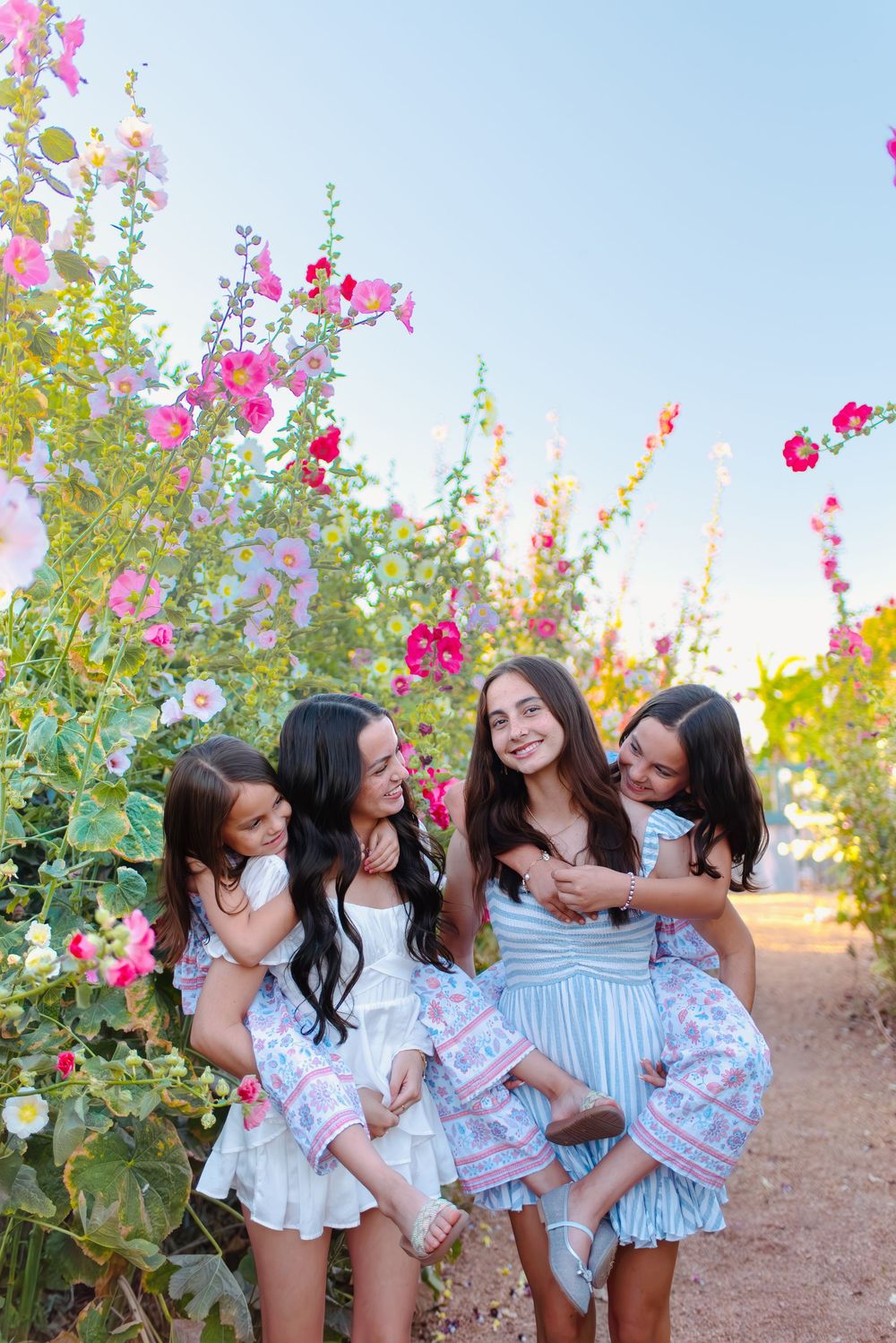 Group of friends enjoying a sunny day together among blooming pink flowers in an outdoor garden setting.