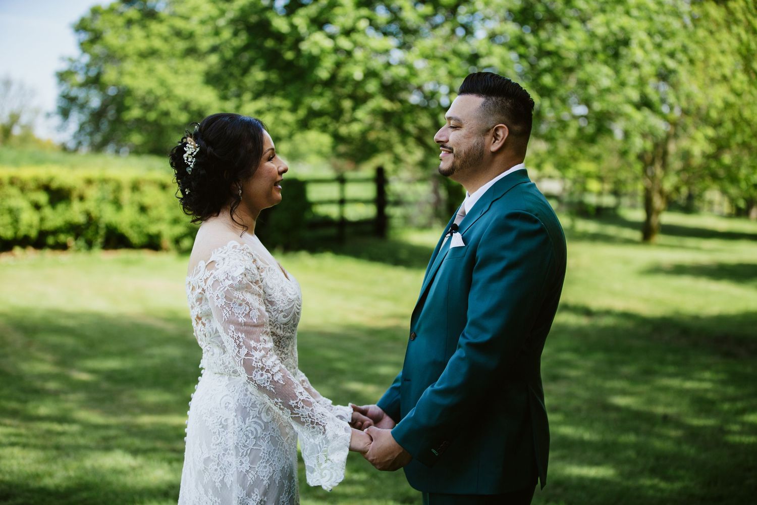 A joyful couple shares a romantic moment on their wedding day in a sunny garden setting with lush greenery.