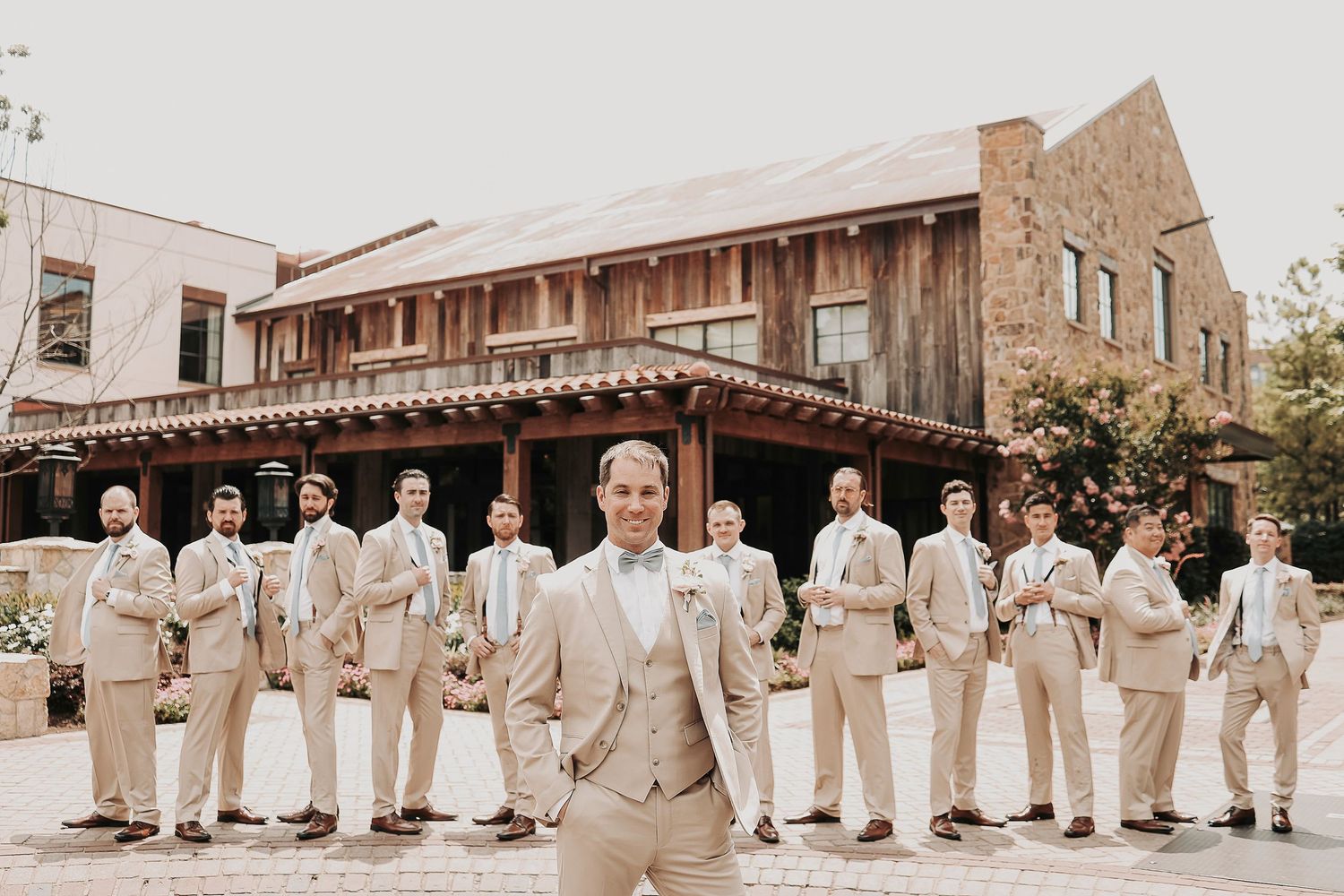 Large Groomsmen Wedding party wearing beige suits and powder blue ties pose in front of the fort worth stockyards