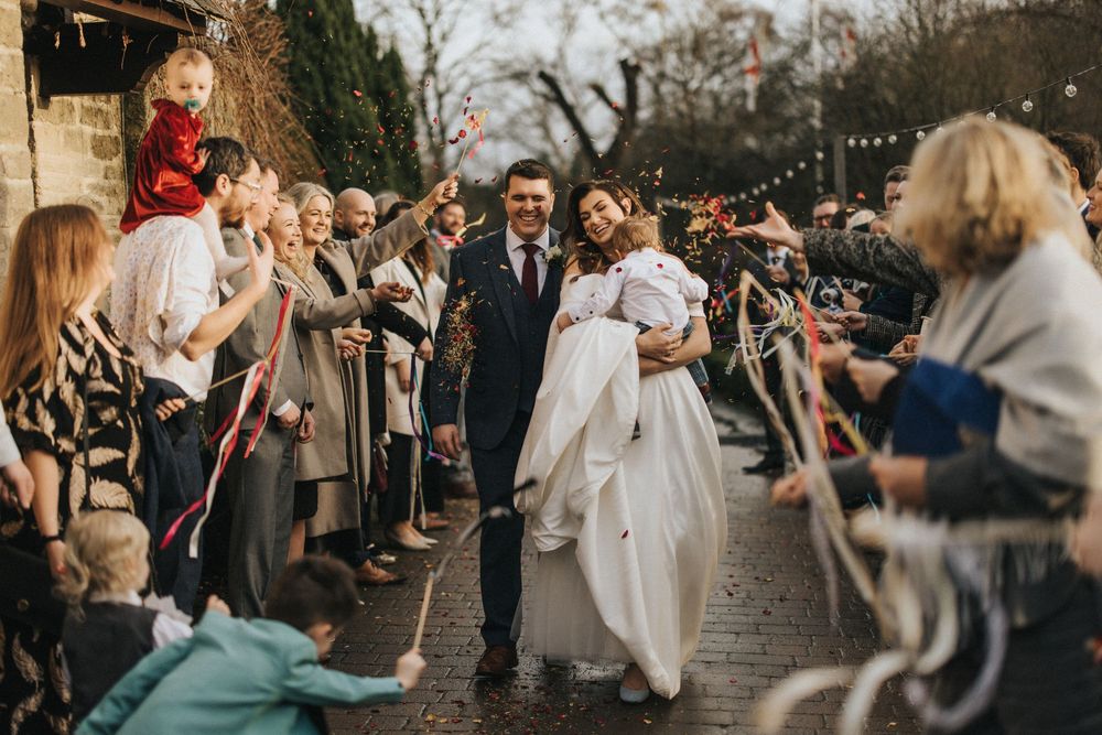 A joyous wedding celebration with guests lining a walkway as the couple exits through a shower of sparklers at dusk.