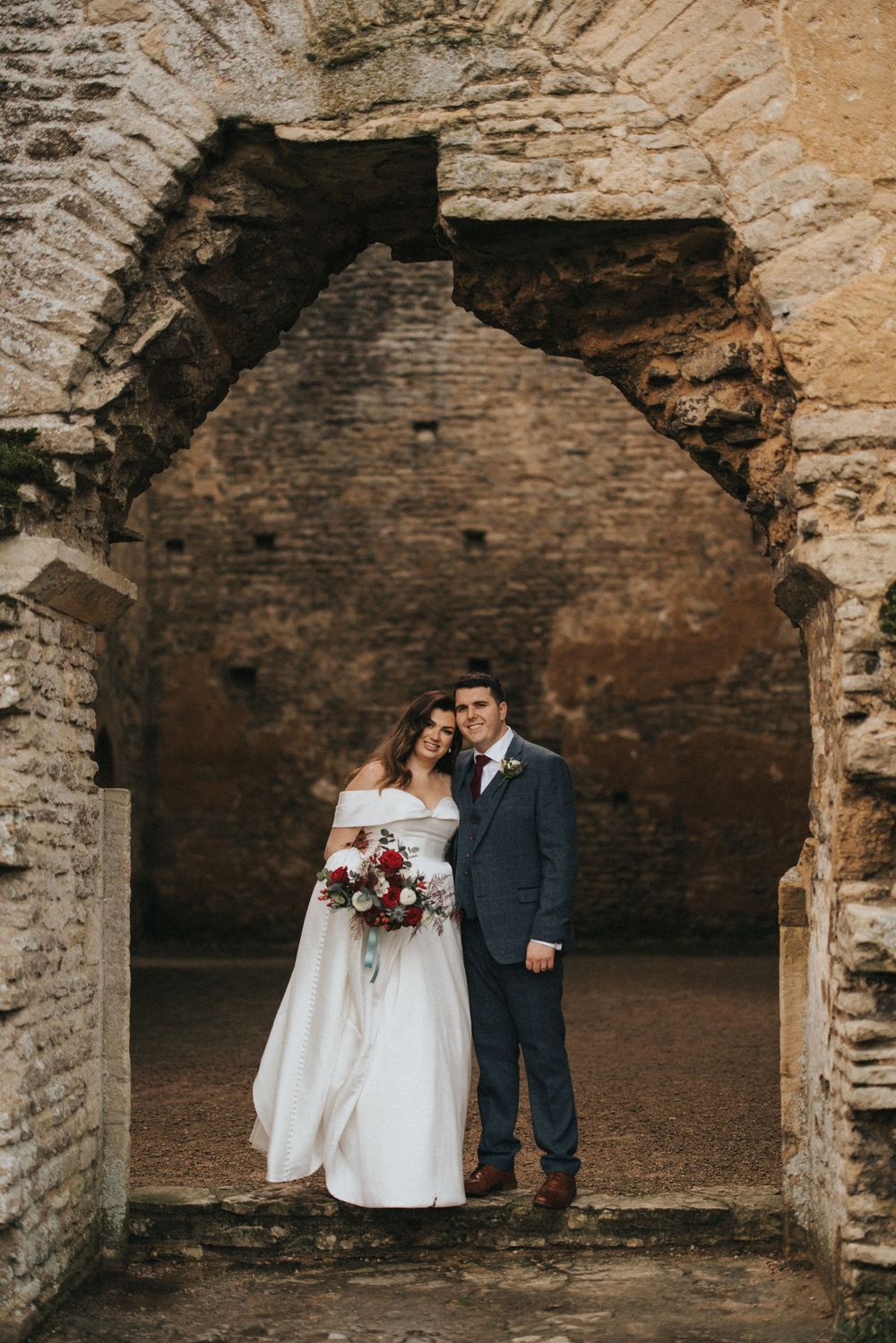 A romantic wedding portrait taken in an archway of rustic stone ruins with rich textural details.