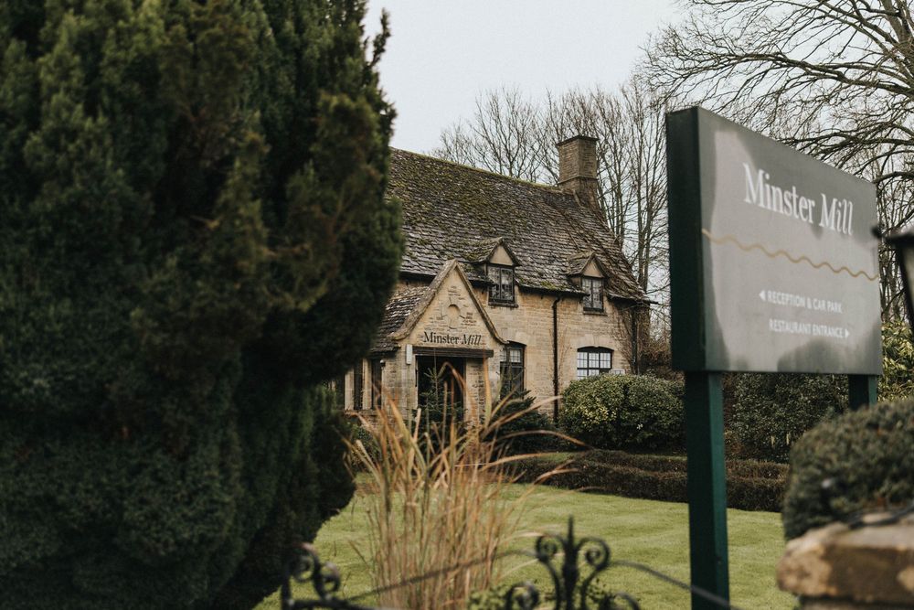 A rustic stone building with a country hotel sign surrounded by evergreen trees and winter foliage.