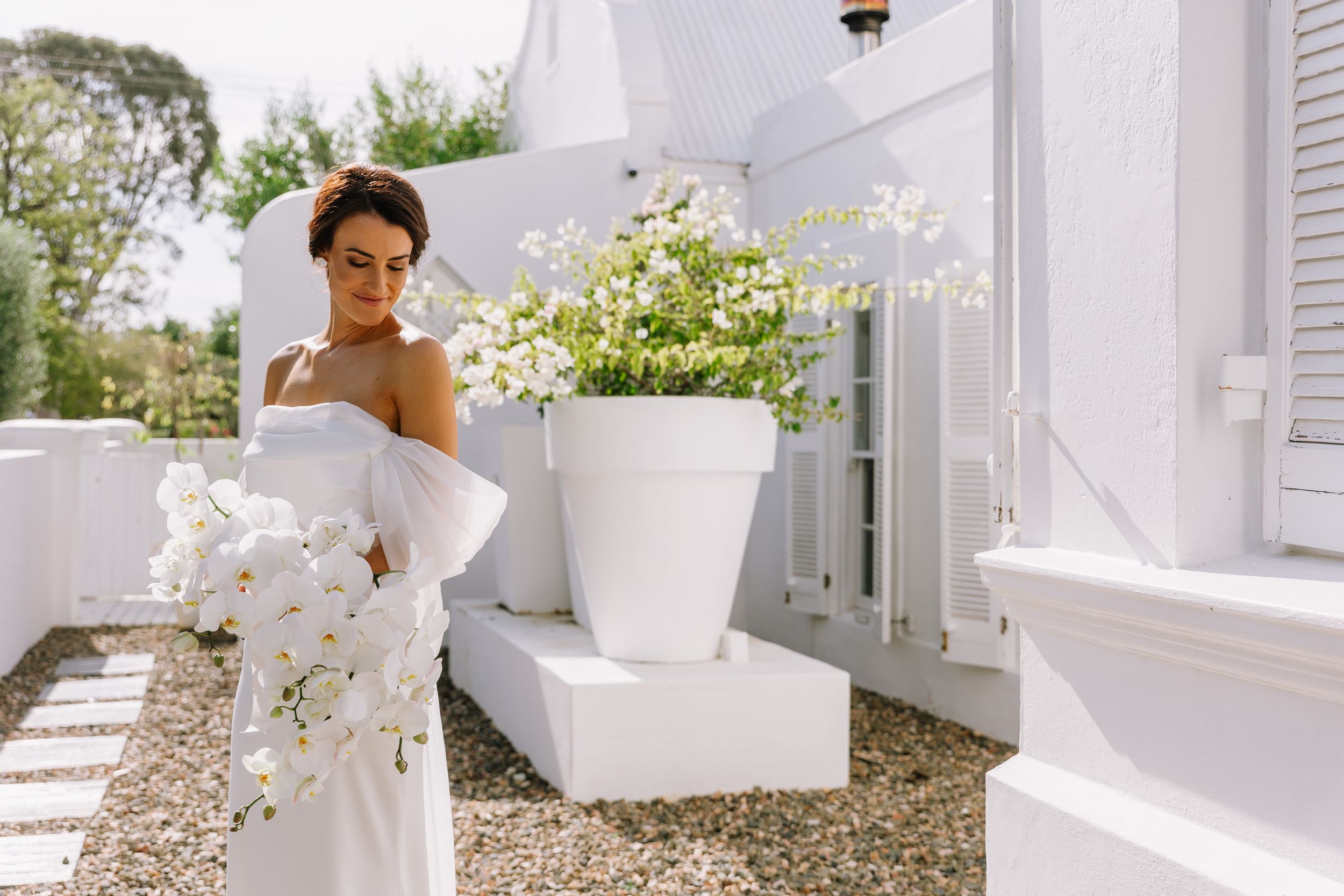 An elegant white bridal dress flows gracefully across multiple connected images in an outdoor garden setting.