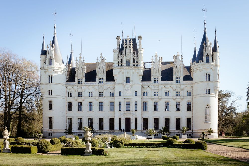 The majestic Challain-la-Potherie castle in France features white Gothic architecture with pointed spires and ornate gardens.