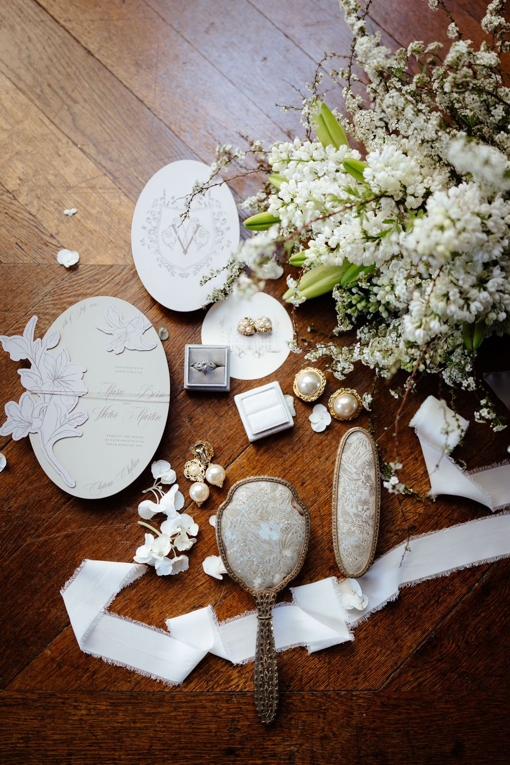 White petals and ring details scattered on a dark wooden surface with elegant styling.