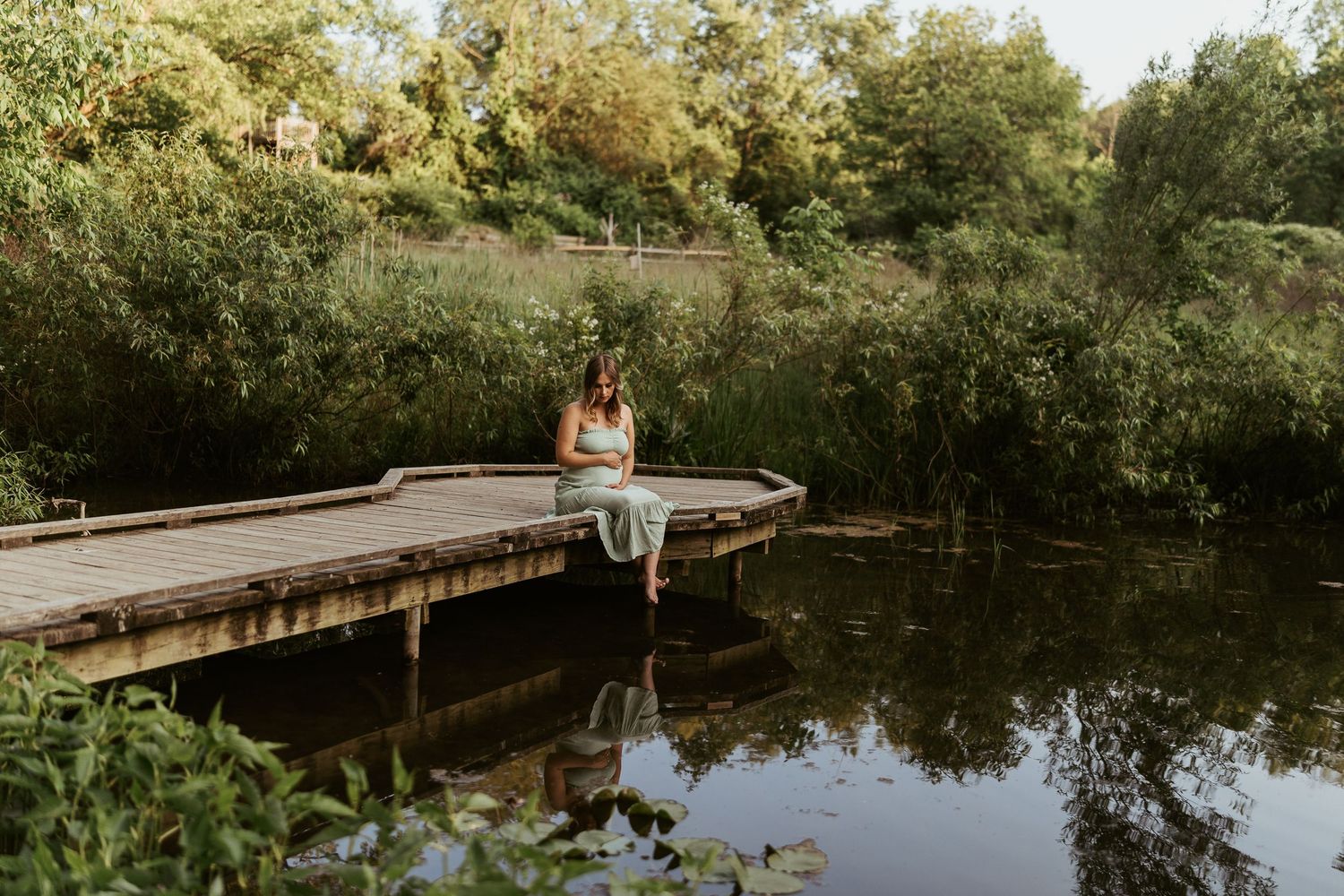 maternity photos in pittsburgh pennsylvania by ash coniglio photography, woman sits on a dock, looking at the water