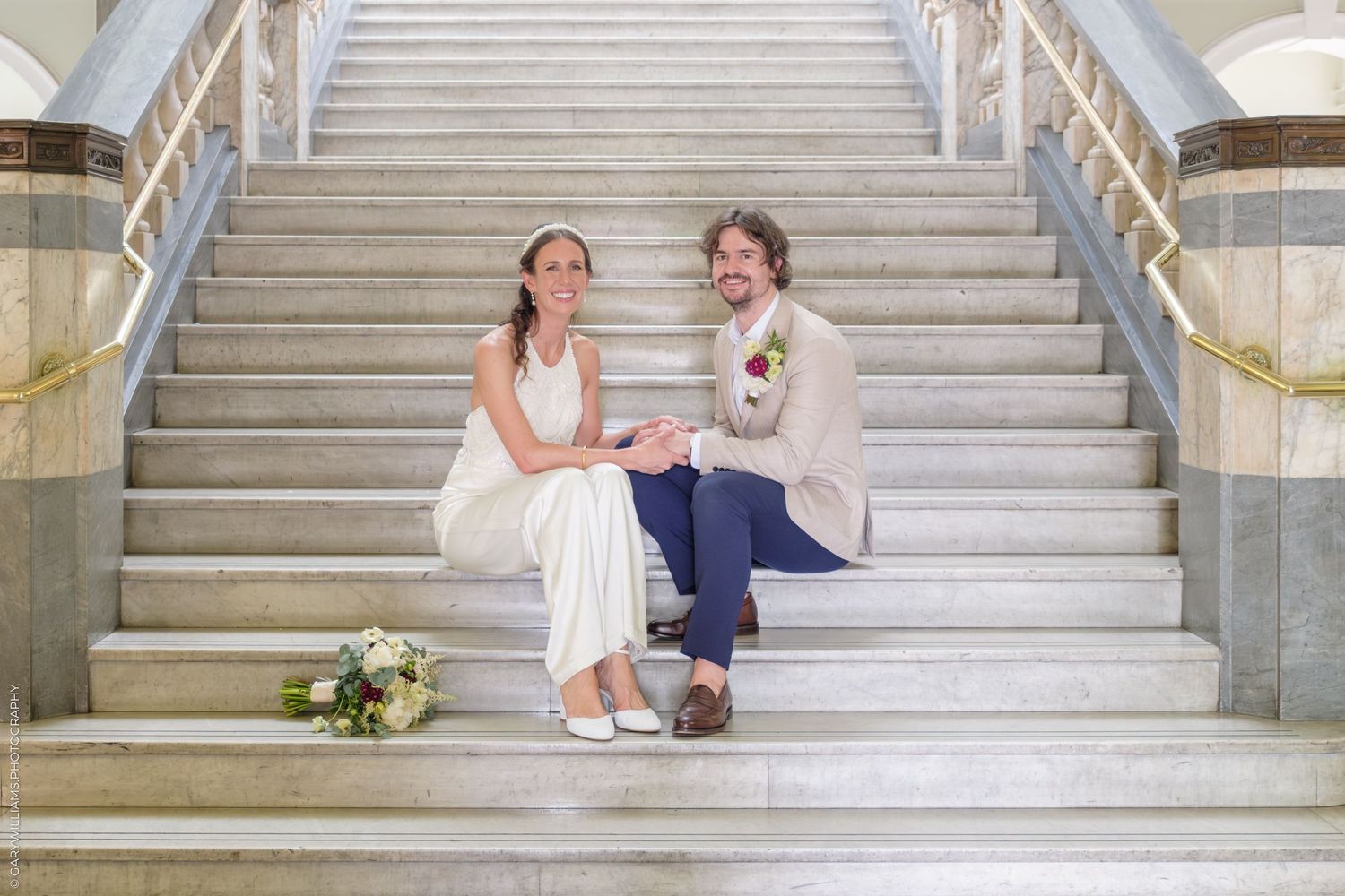 Couple sitting and sharing romantic moments on an elegant white marble staircase with classic architectural details.