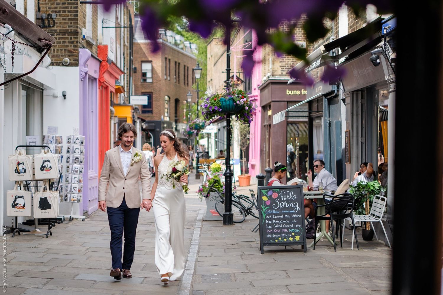 A happy couple walks down a charming cobblestone street lined with colorful shops and outdoor cafes.