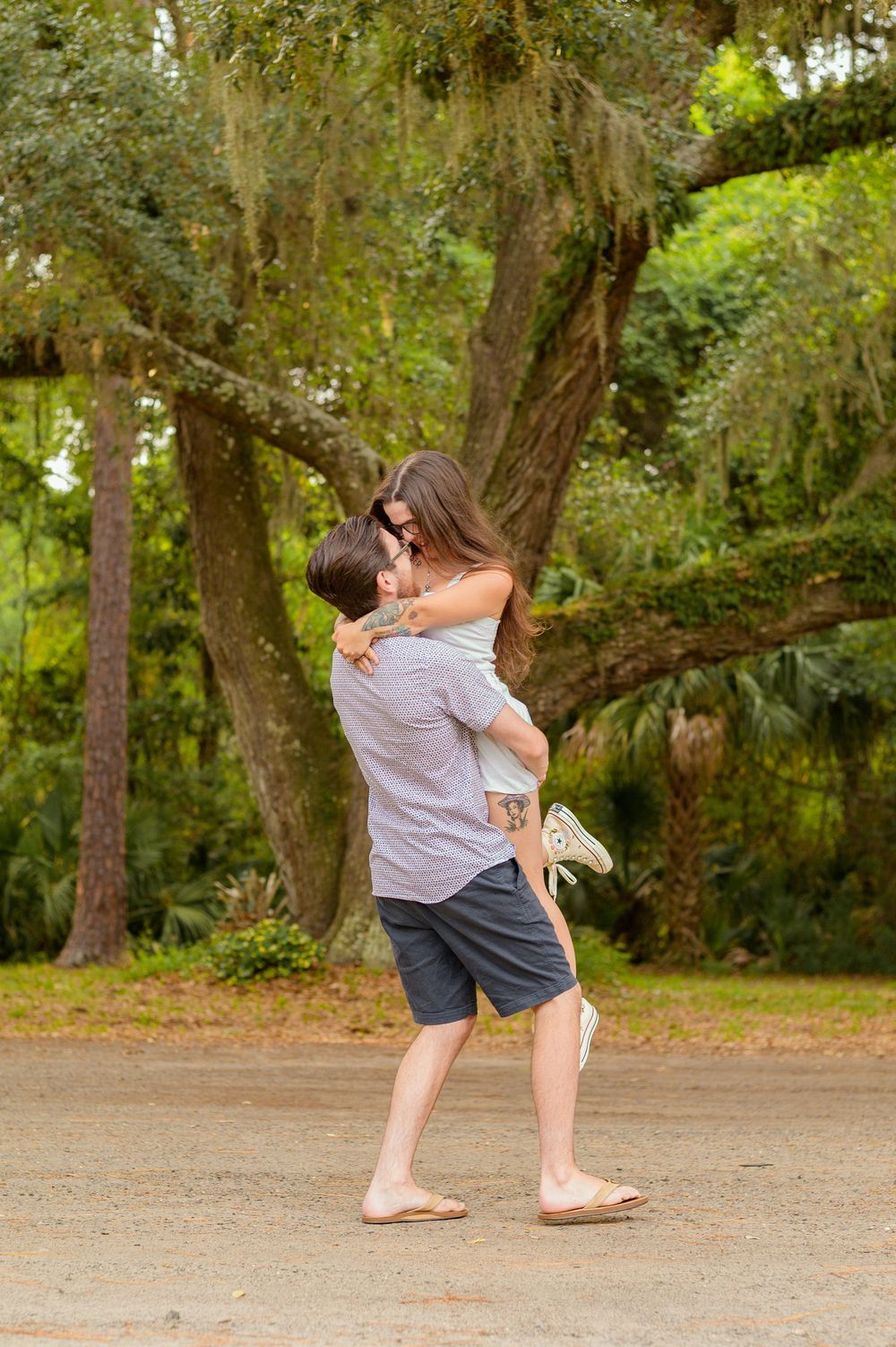 Couple sharing a romantic embrace among Spanish moss-draped trees.