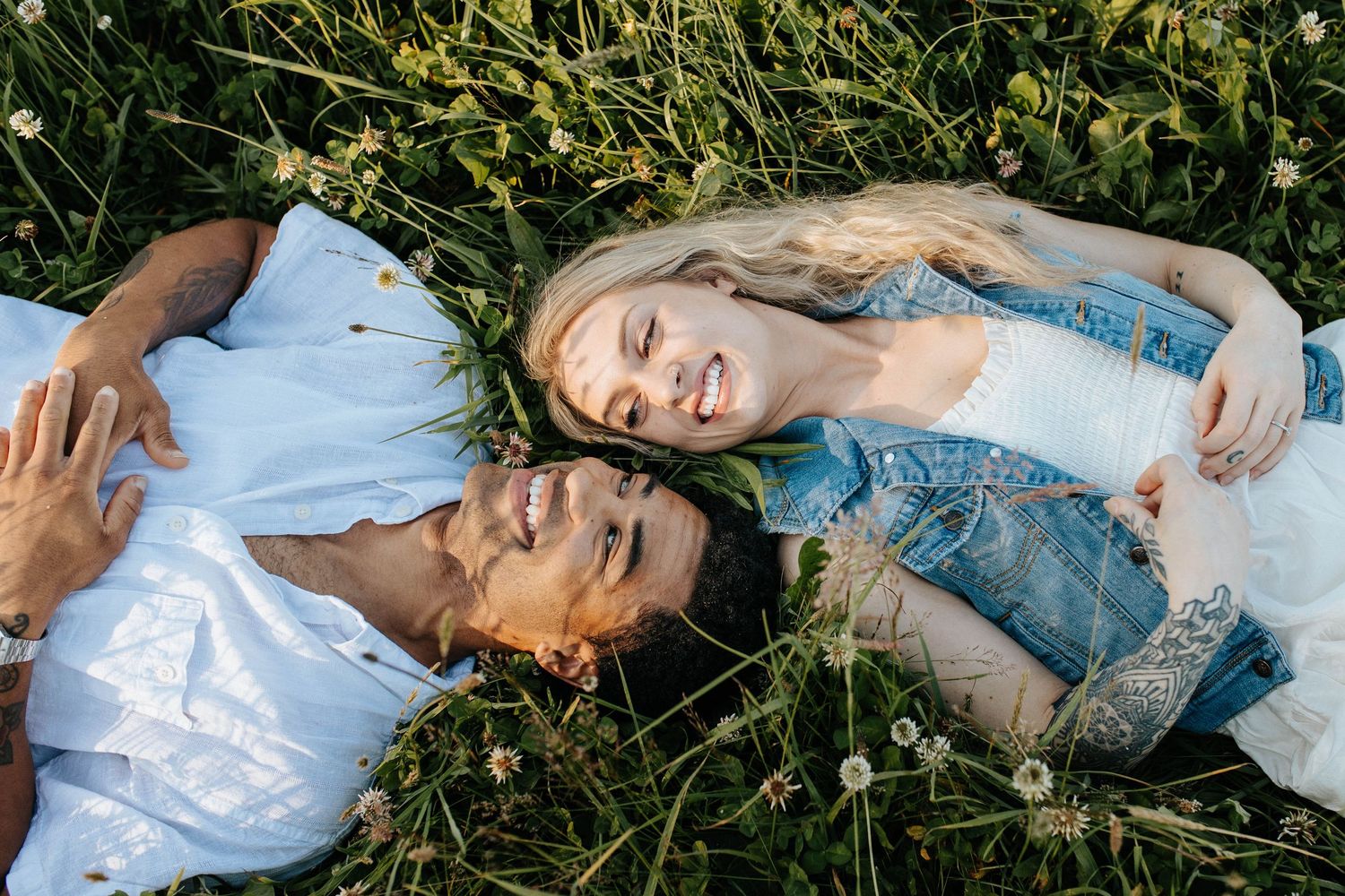 A woman in a blue dress lies serenely in lush green grass during a springtime outdoor photo session.