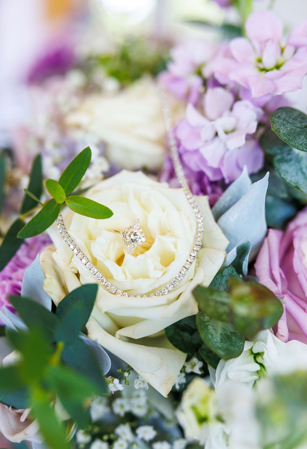 Wedding bouquet with cream roses, pink flowers and diamond rings nestled in the petals.