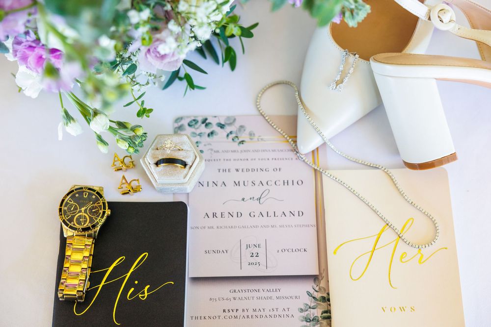 Wedding invitation with white heels and floral decorations on a light background surrounded by gold accents.