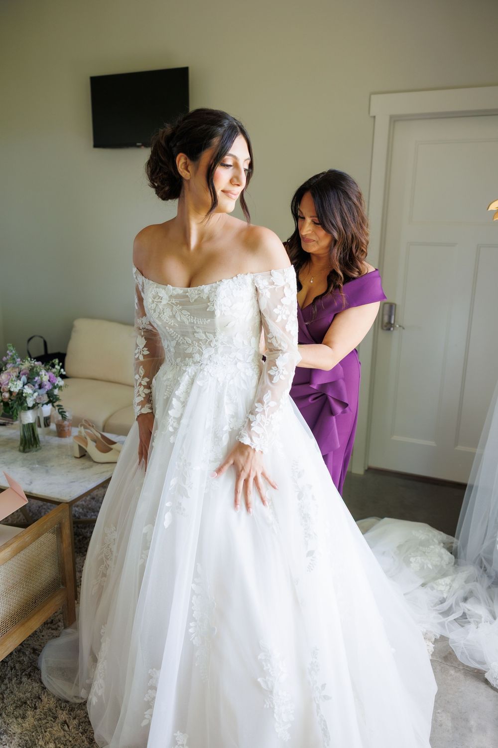 Elegant white wedding dress with lace sleeves and full tulle skirt being prepared for the bride.