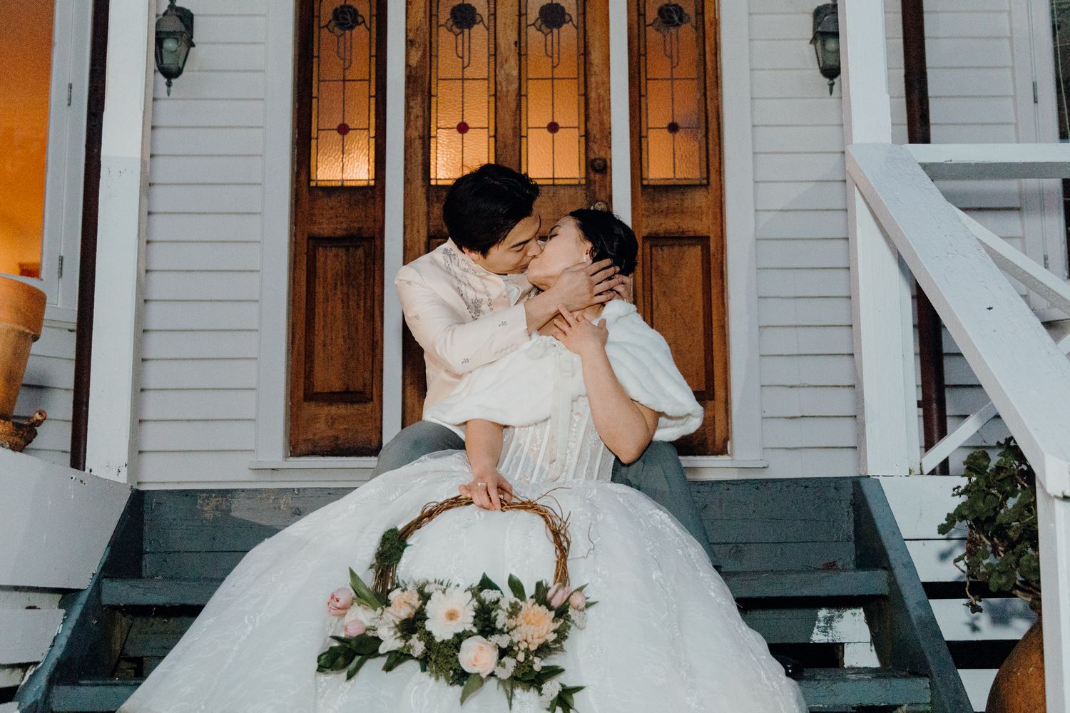 Romantic moment captured on white church steps with elegant bridal attire.
