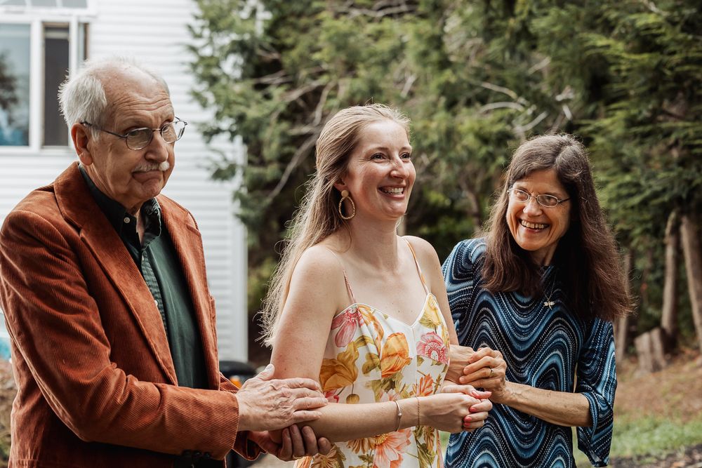 Three people share a candid laughing moment together outdoors.