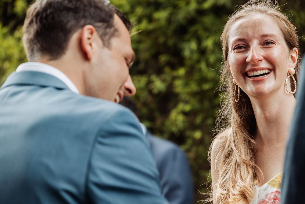 Two people sharing a joyful moment of laughter during an outdoor gathering.