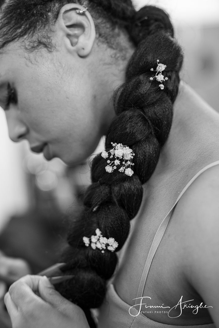 A candid, black and white close-up of Paige sporting a single braid decorated with delicate white flowers