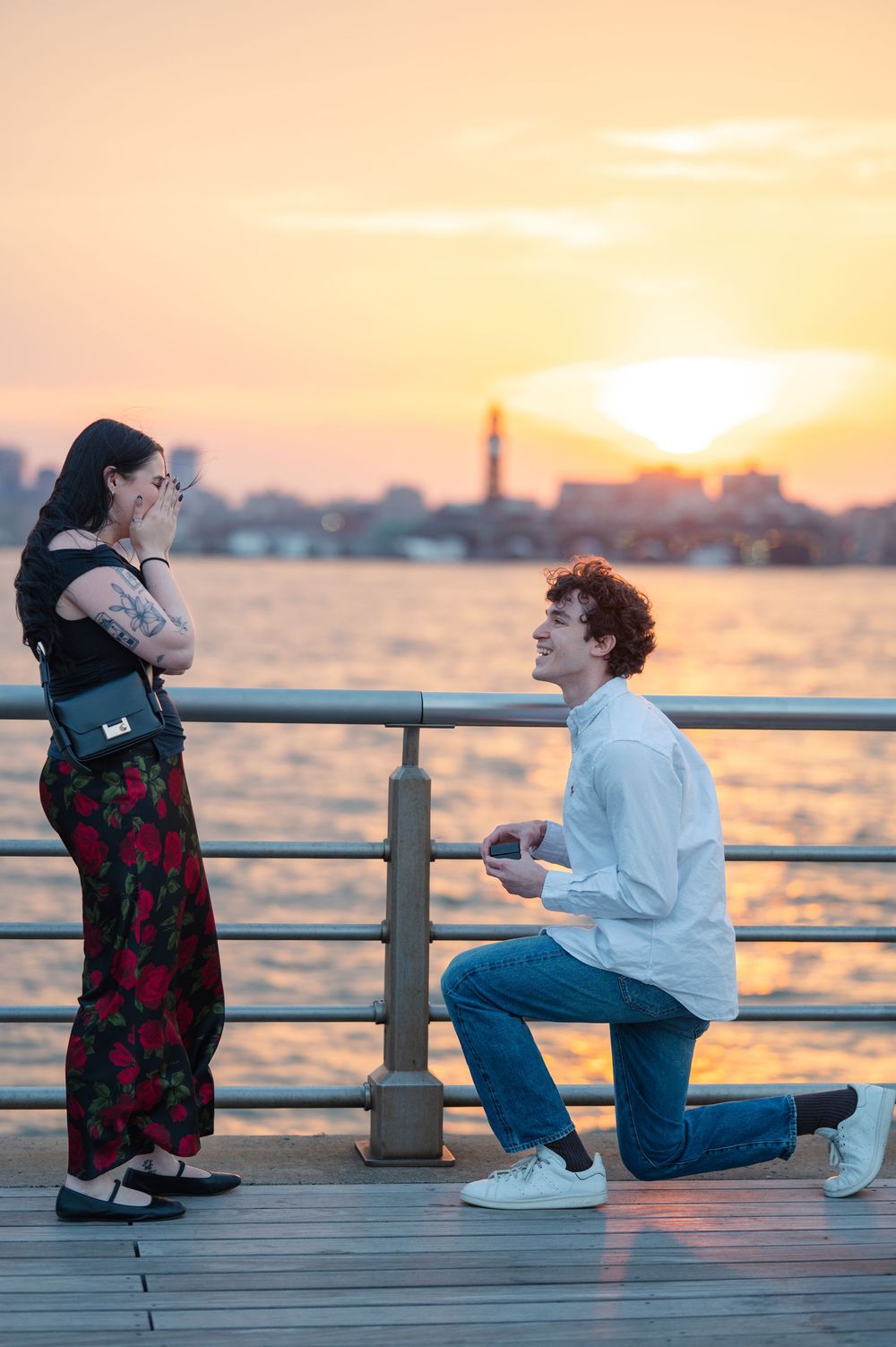 A romantic sunset proposal moment at Pier 45 at Hudson Park with a glowing orange sky over the harbor in NYC