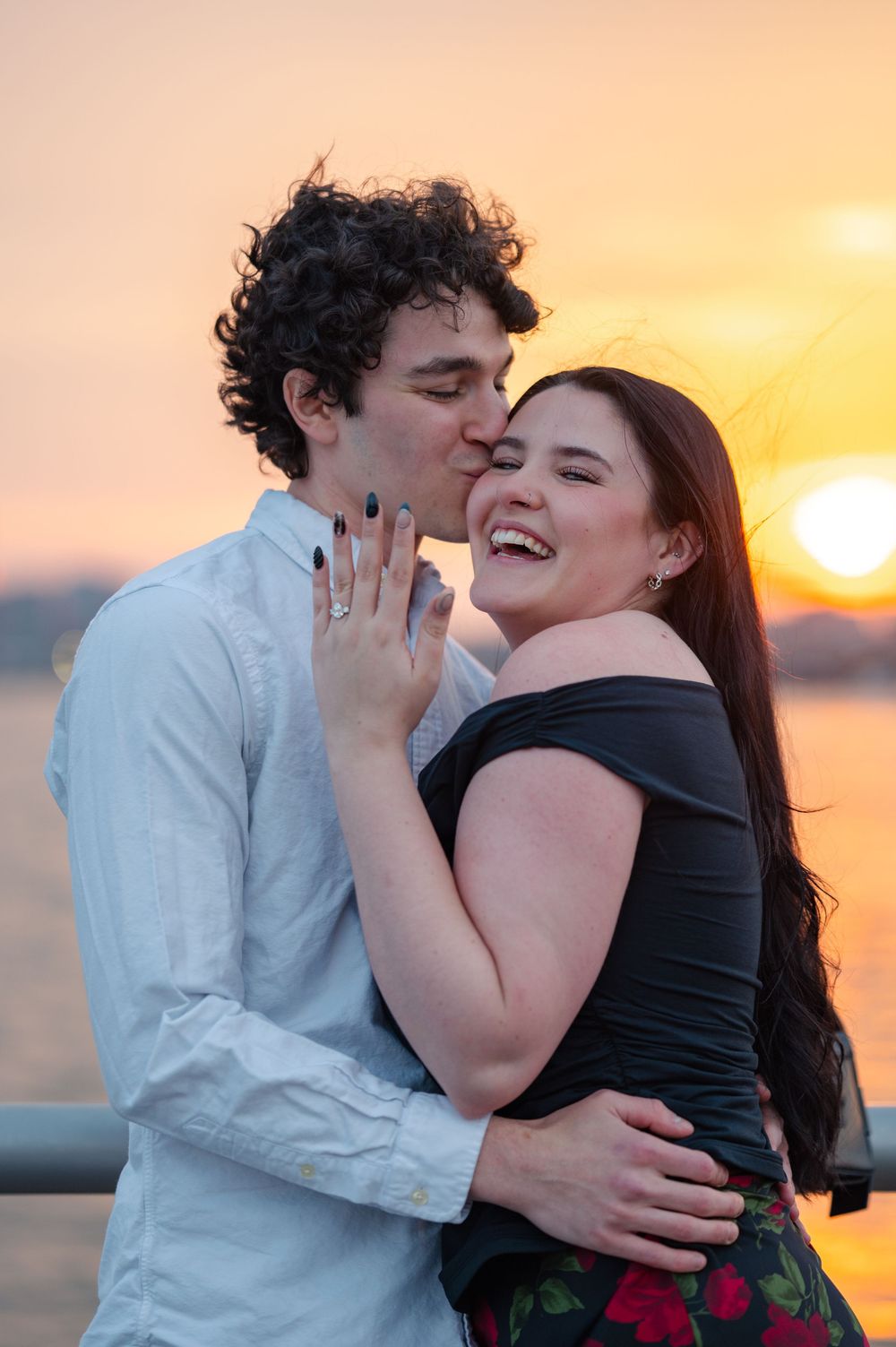 Romantic couple embracing during golden sunset with cityscape in background after their proposal