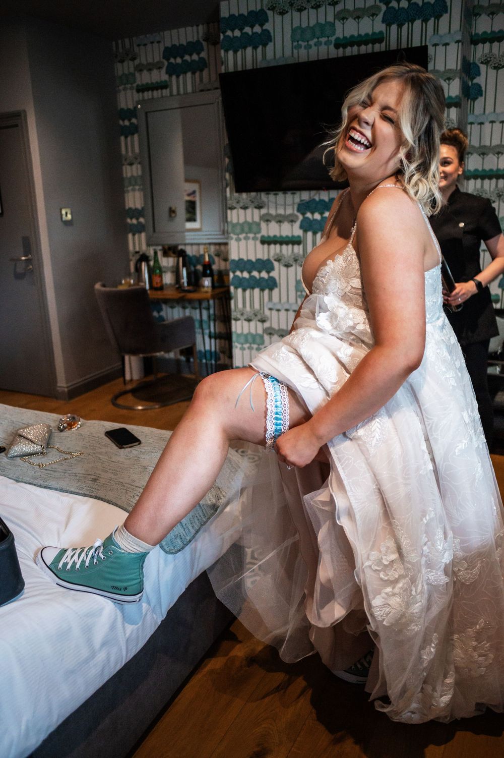 Candid moment showing bride seated wearing turquoise sneakers with her wedding dress.