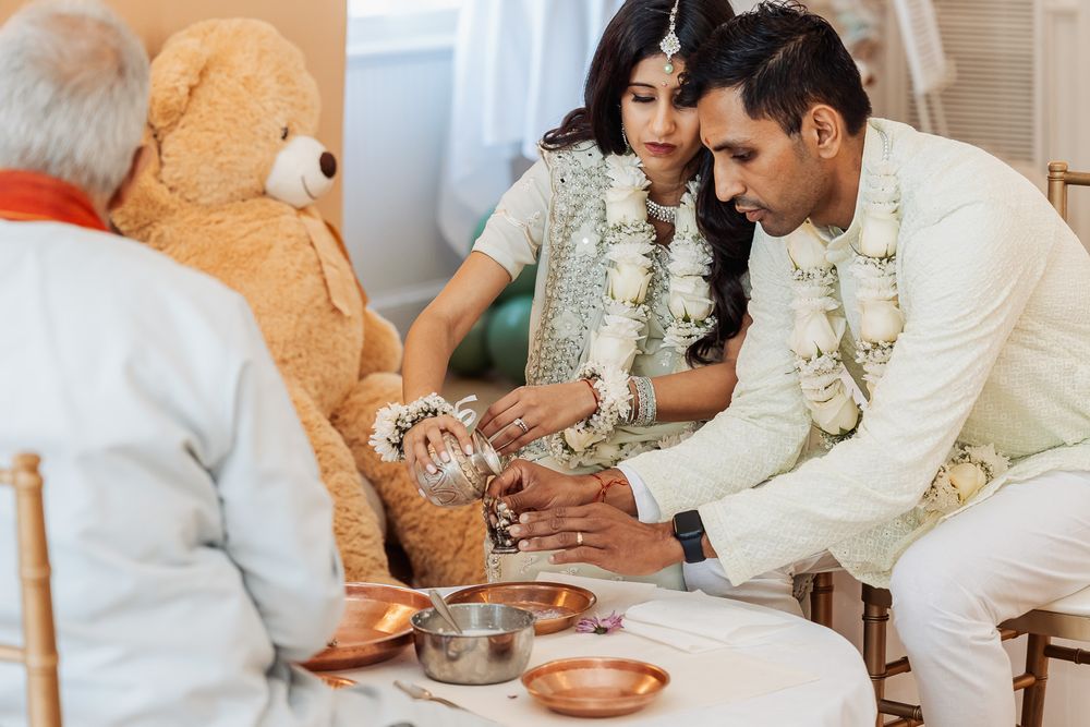 A couple performs ceremonial rituals with bowls and offerings during a traditional ceremony.