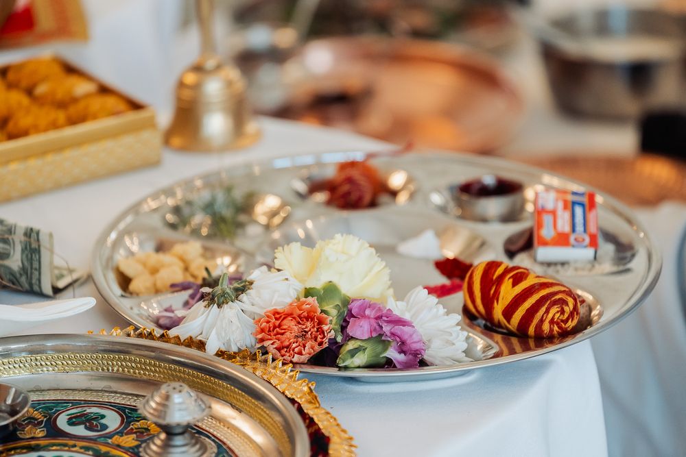 Elegant platter of colorful traditional Indian appetizers and decorative items arranged on a white tablecloth.