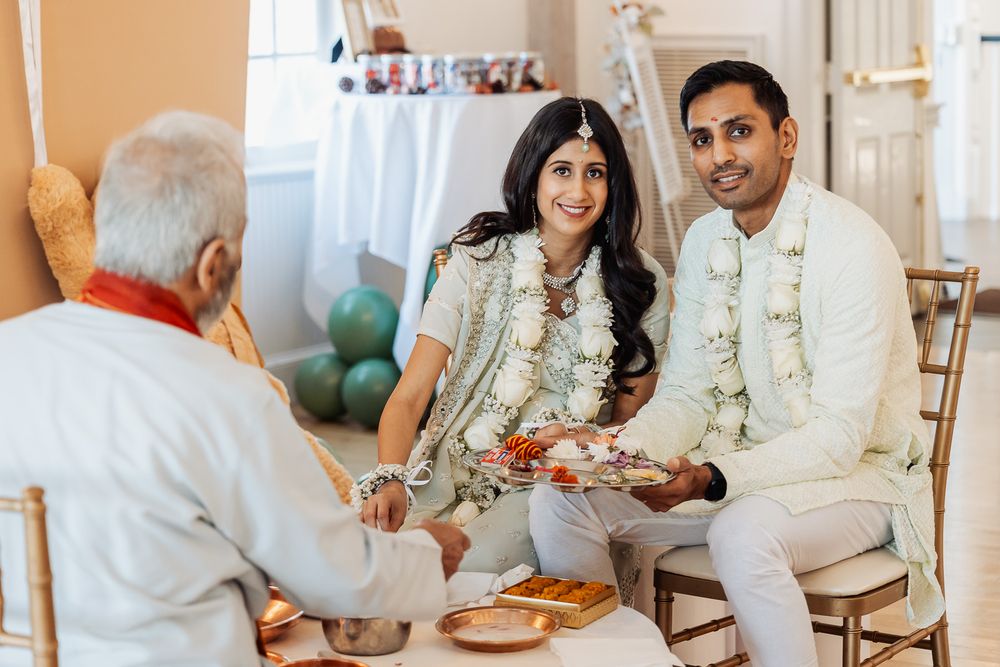 Traditional Hindu wedding ceremony with participants in white and cream colored attire.