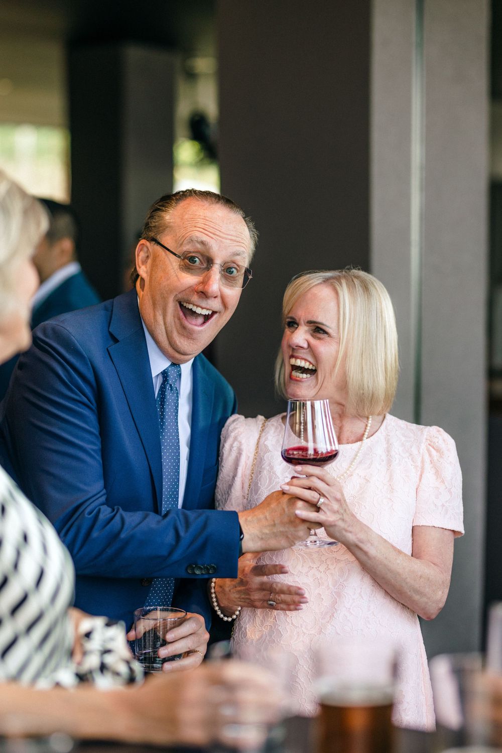 A joyful moment shared between guests enjoying wine at an elegant celebration.