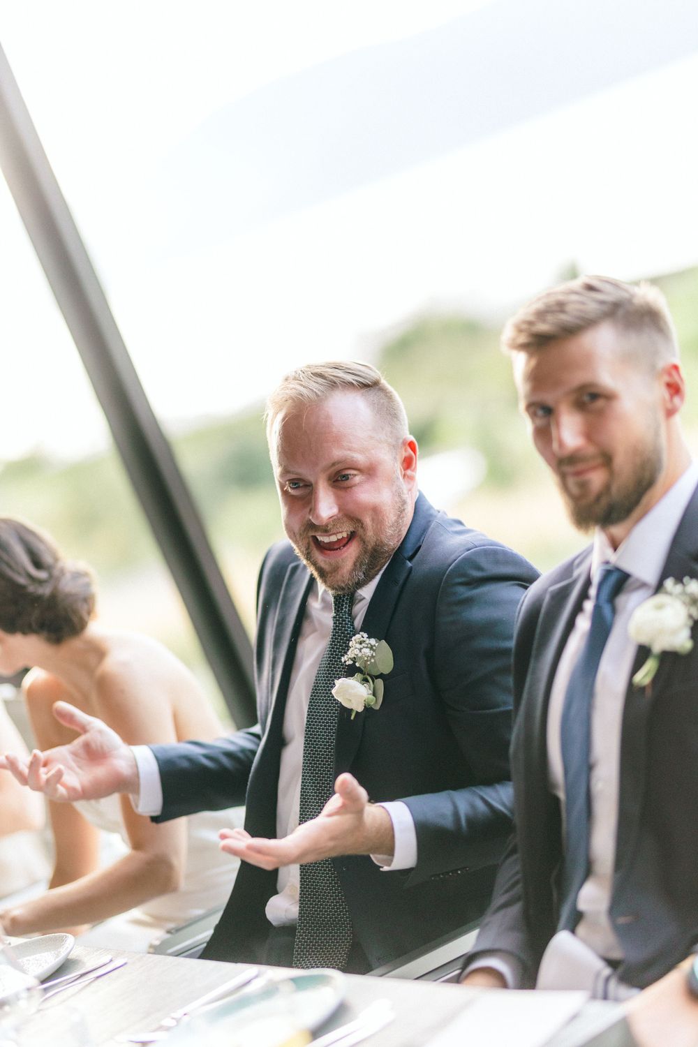 Wedding guests share a candid moment of laughter during an outdoor celebration.