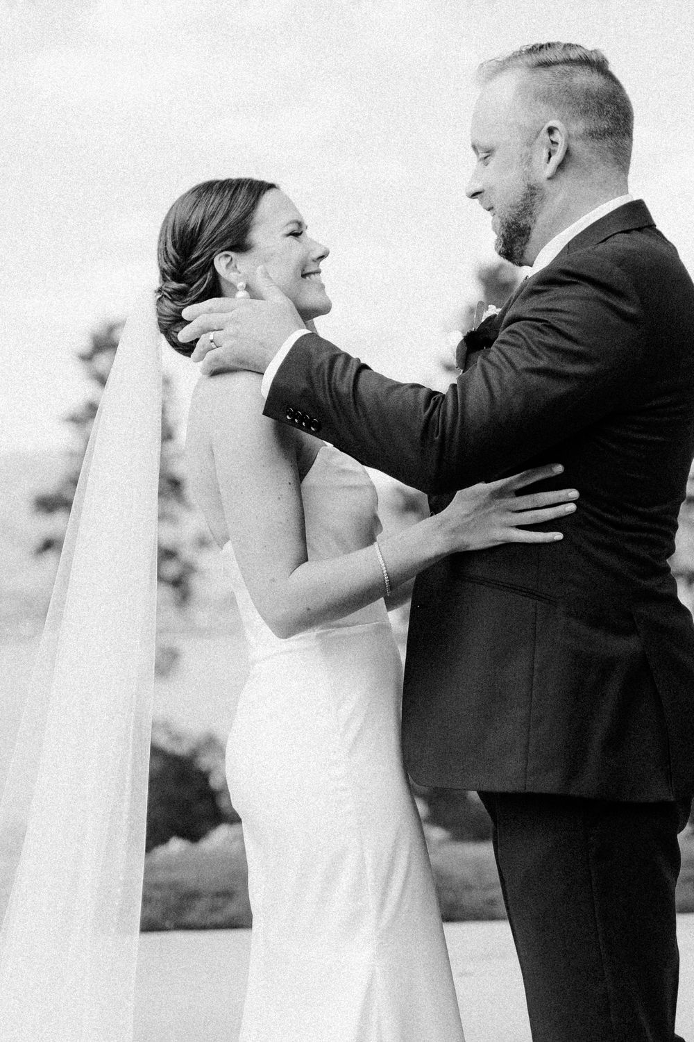 Black and white photo of newlywed couple sharing an intimate moment during their wedding ceremony outdoors.