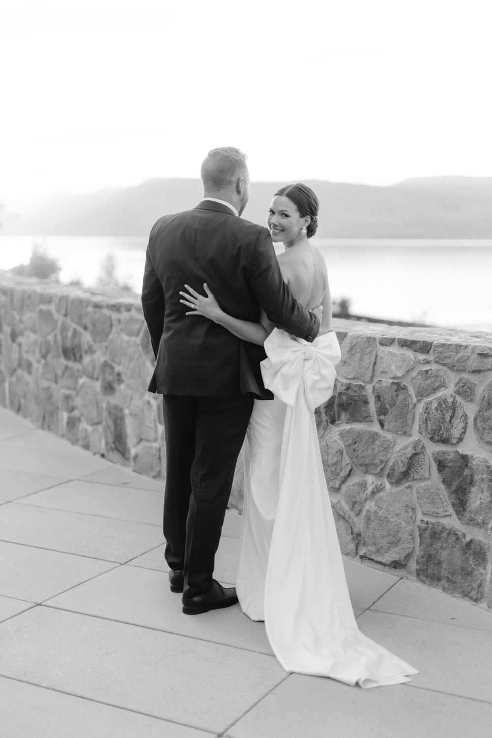 Romantic black and white portrait of newlyweds overlooking a scenic lake view.