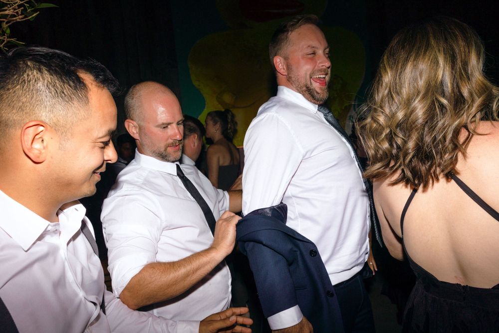 People dancing and enjoying themselves at a party celebration in white dress shirts and formal attire.