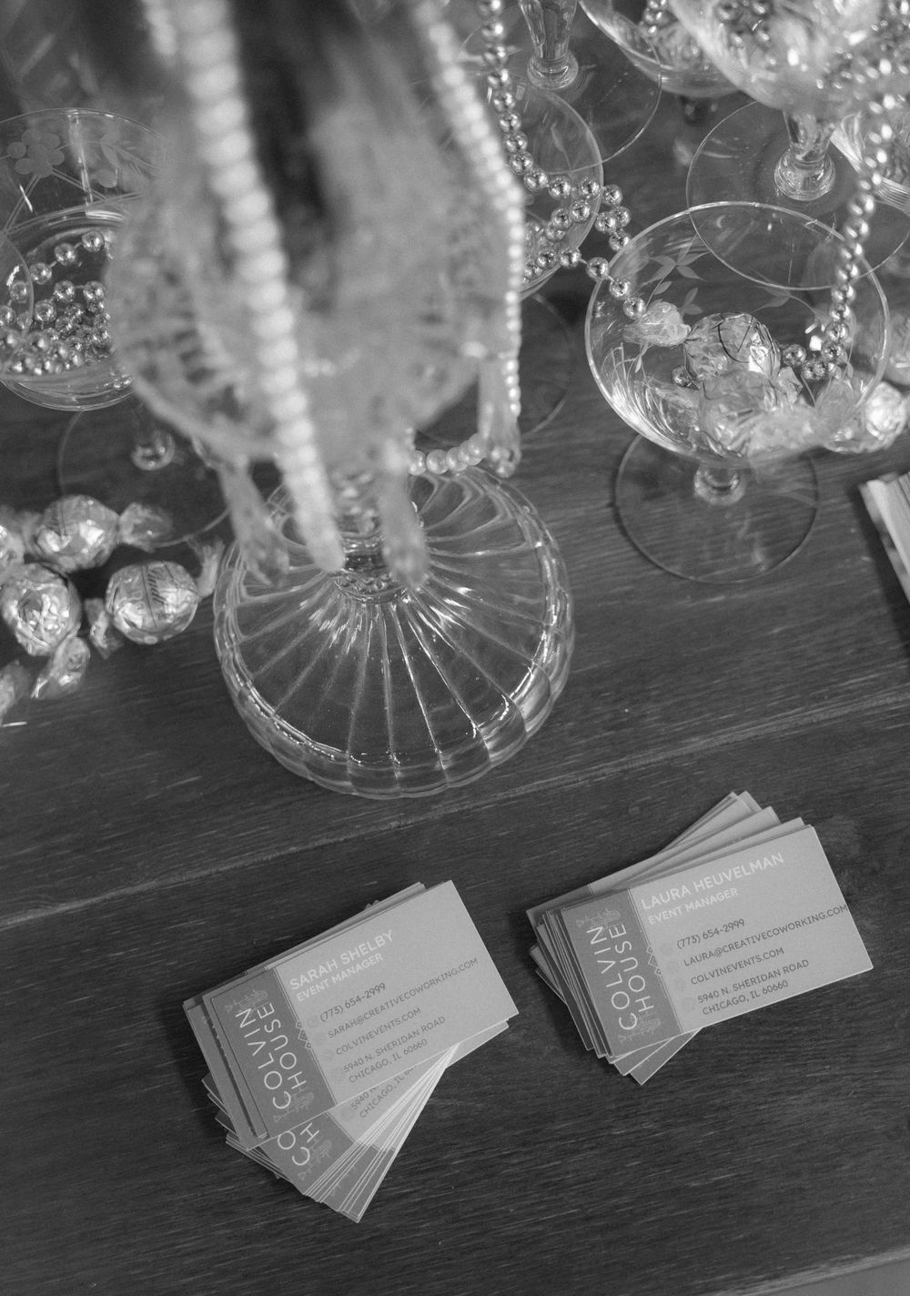 Crystal glassware and business cards arranged on a dark surface in black and white. At Fairlie, Chicago